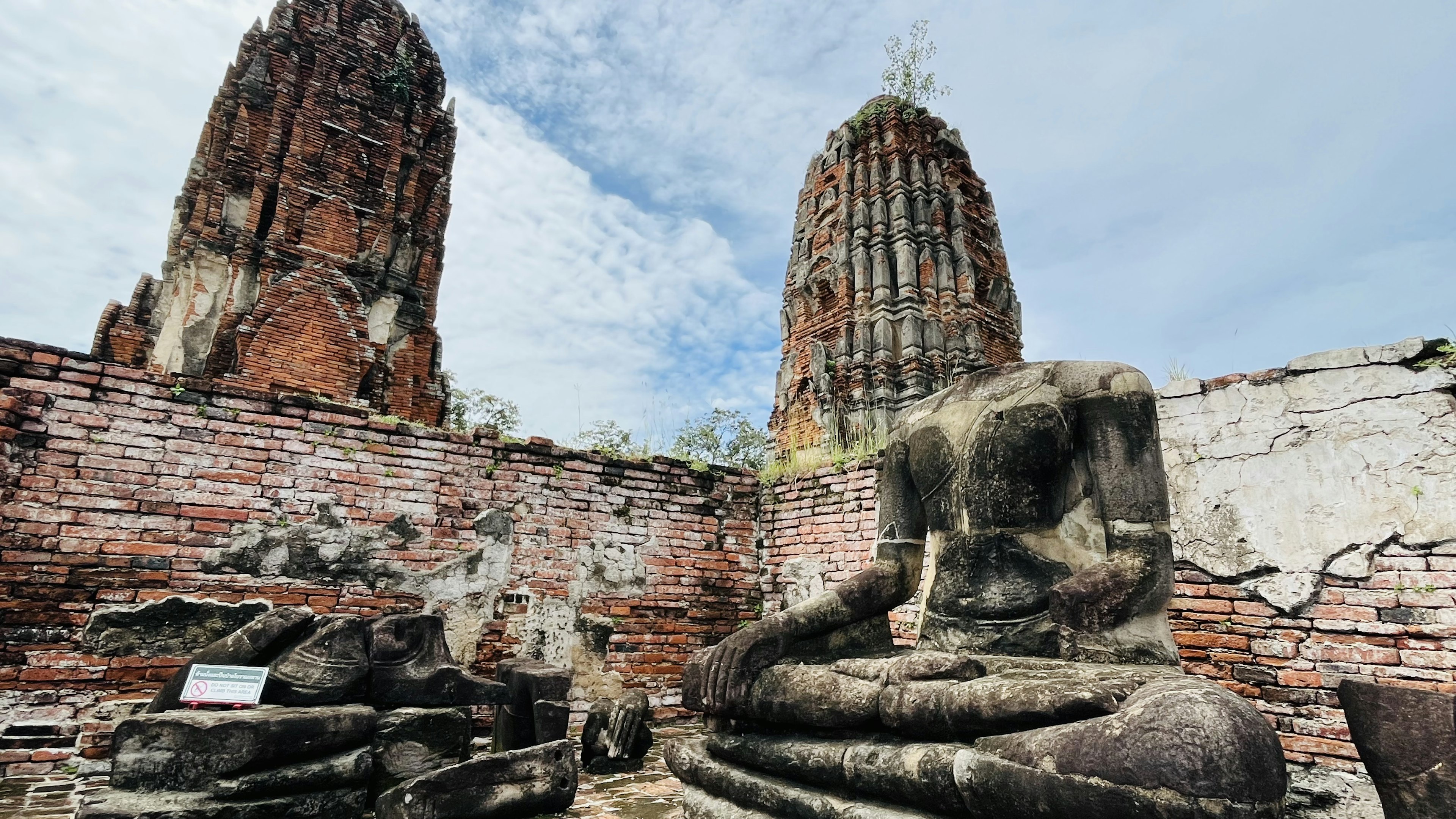 Patung Buddha kuno dengan reruntuhan kuil di latar belakang