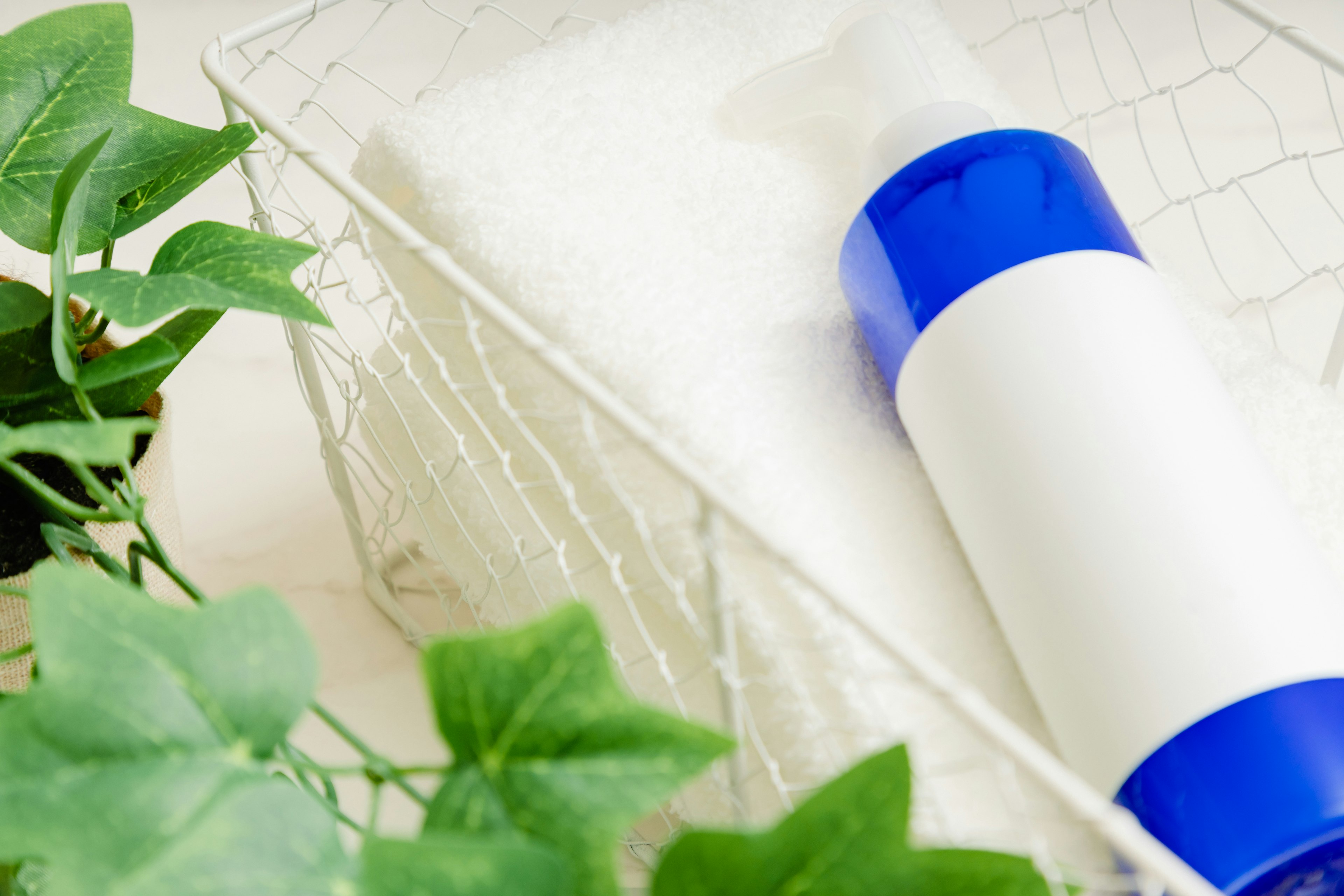 Wire basket containing a blue-capped bottle and a white towel