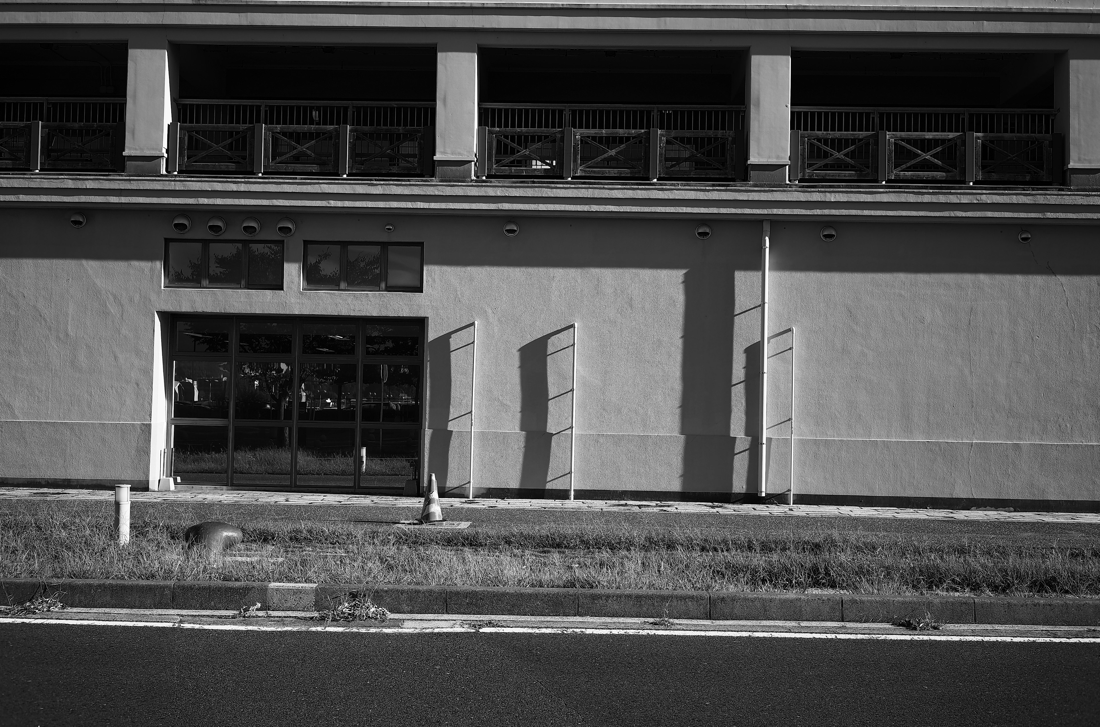 Exterior en blanco y negro de un edificio con una amplia entrada ubicado al borde de la carretera