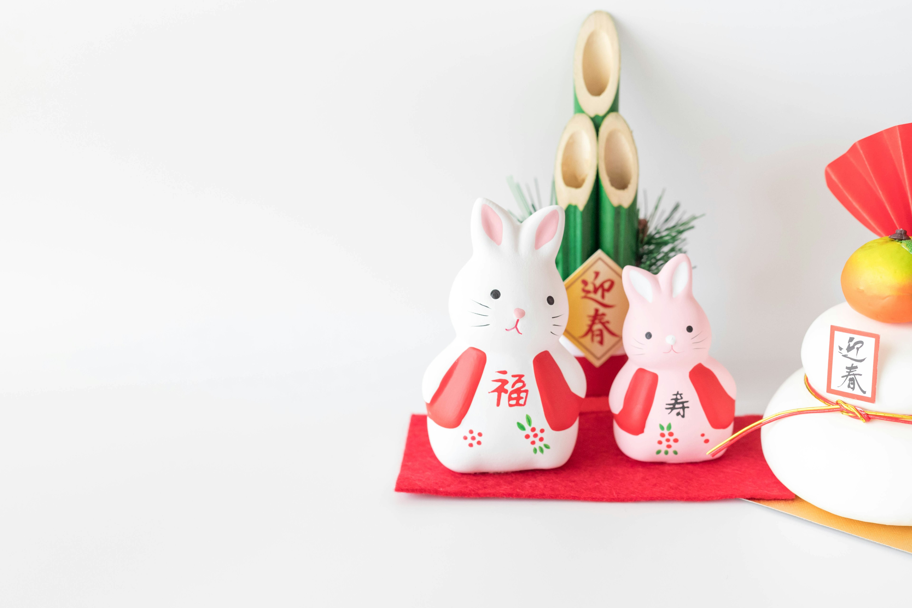 Ceramic rabbit figurines with bamboo decoration on a white background