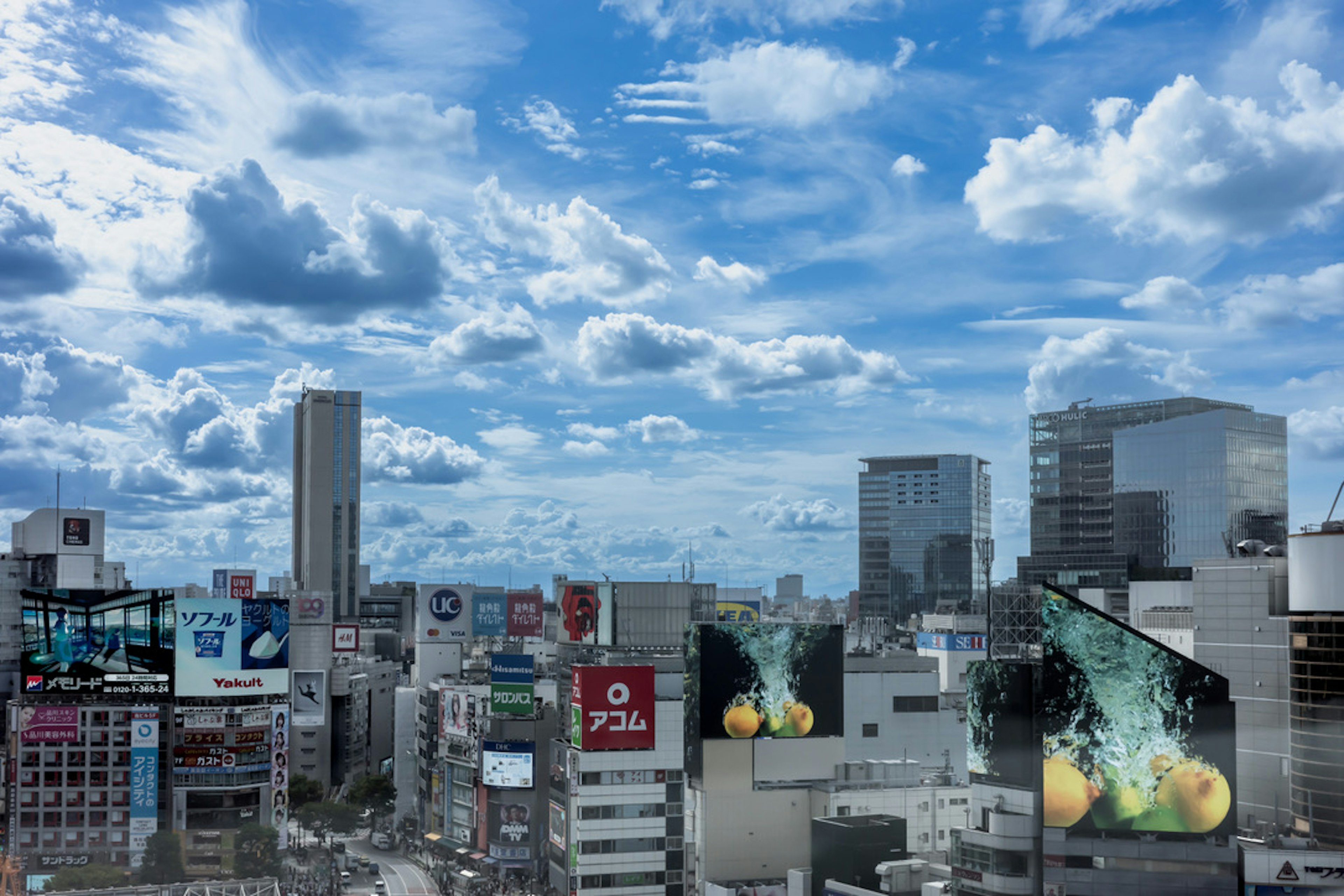 青空と雲が広がる都市の風景ビルと広告が映る