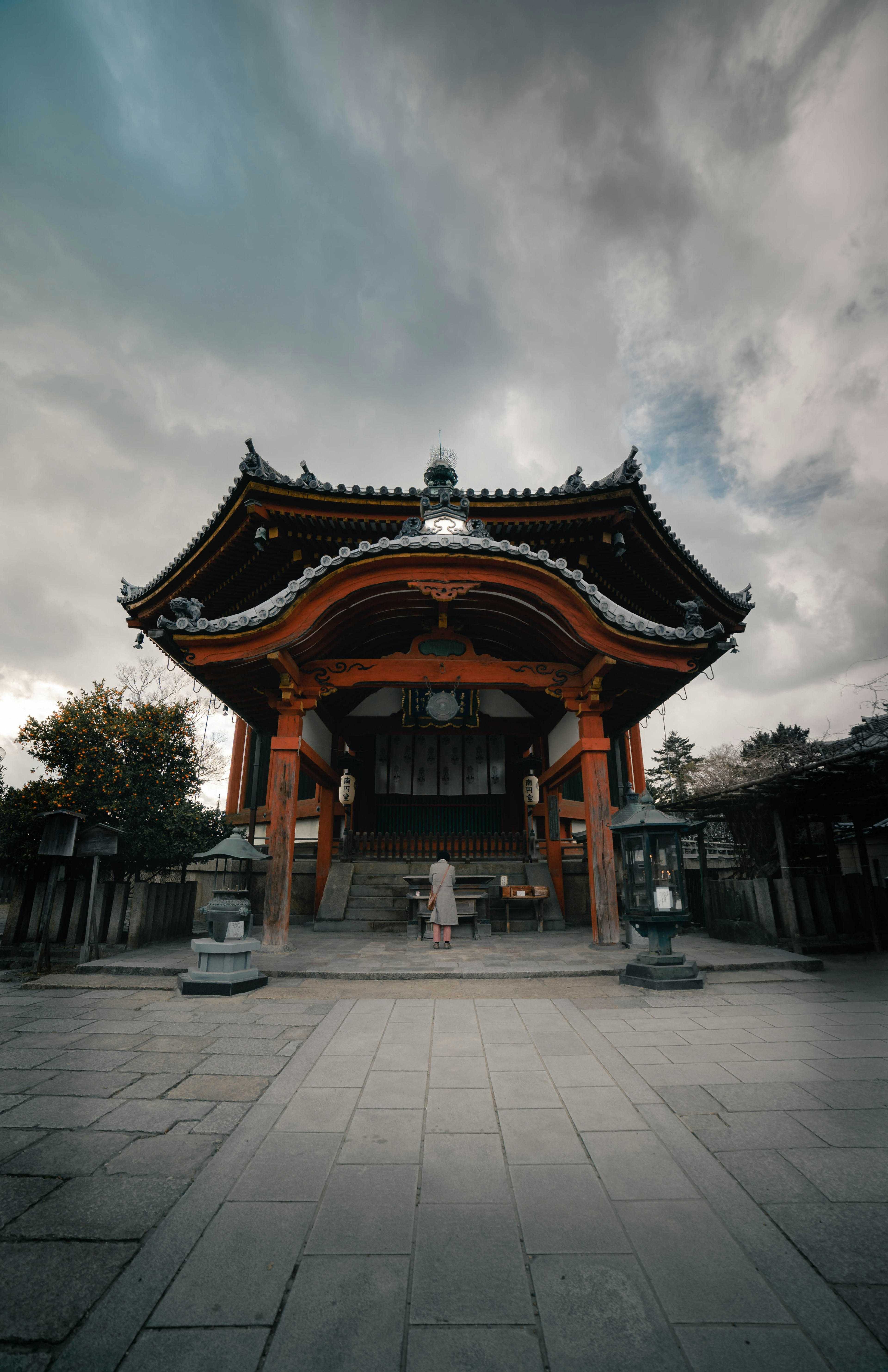 传统建筑风格的寺庙外观，木柱和屋顶在阴云密布的天空下