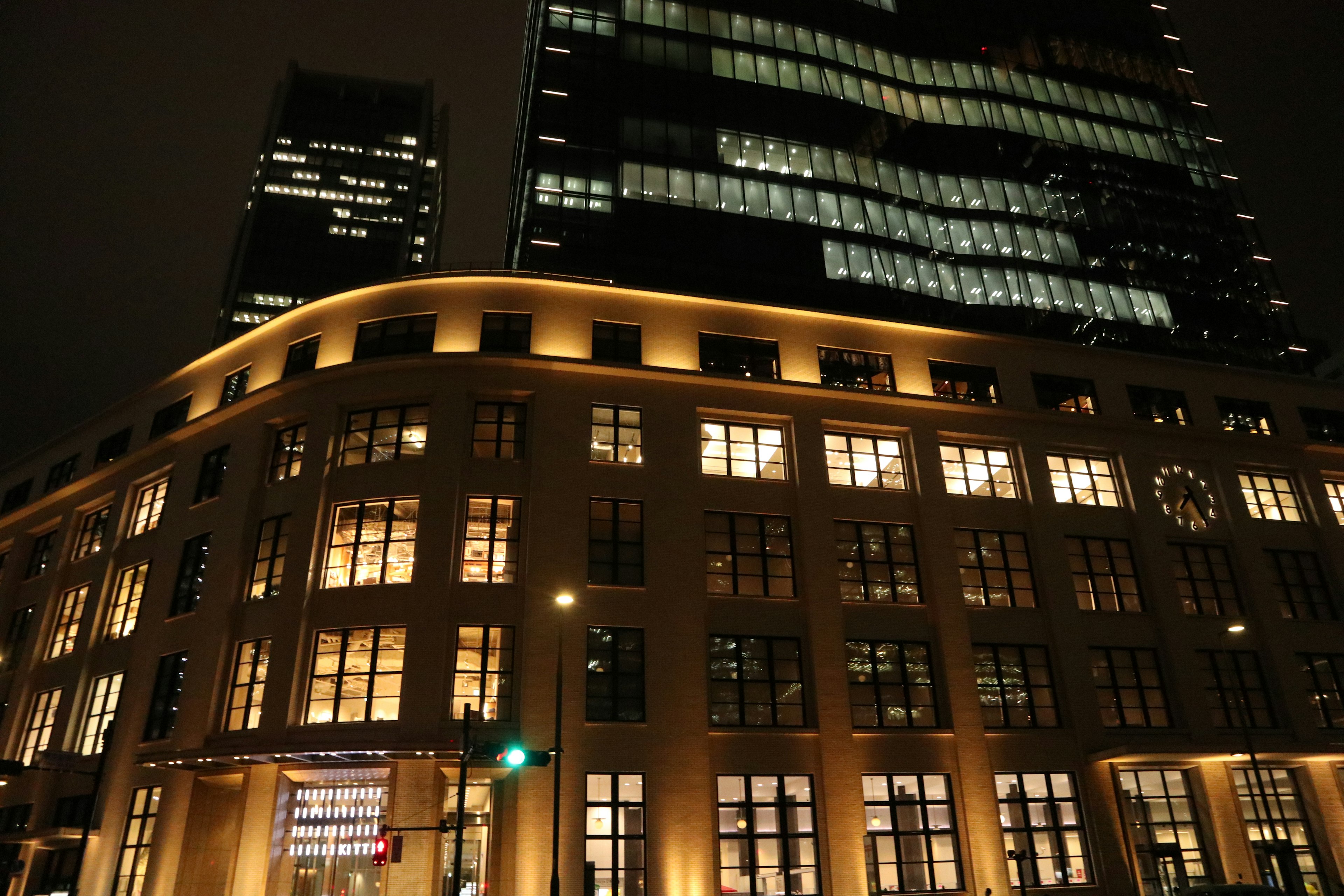 Edificio storico con finestre illuminate e grattacielo moderno di notte