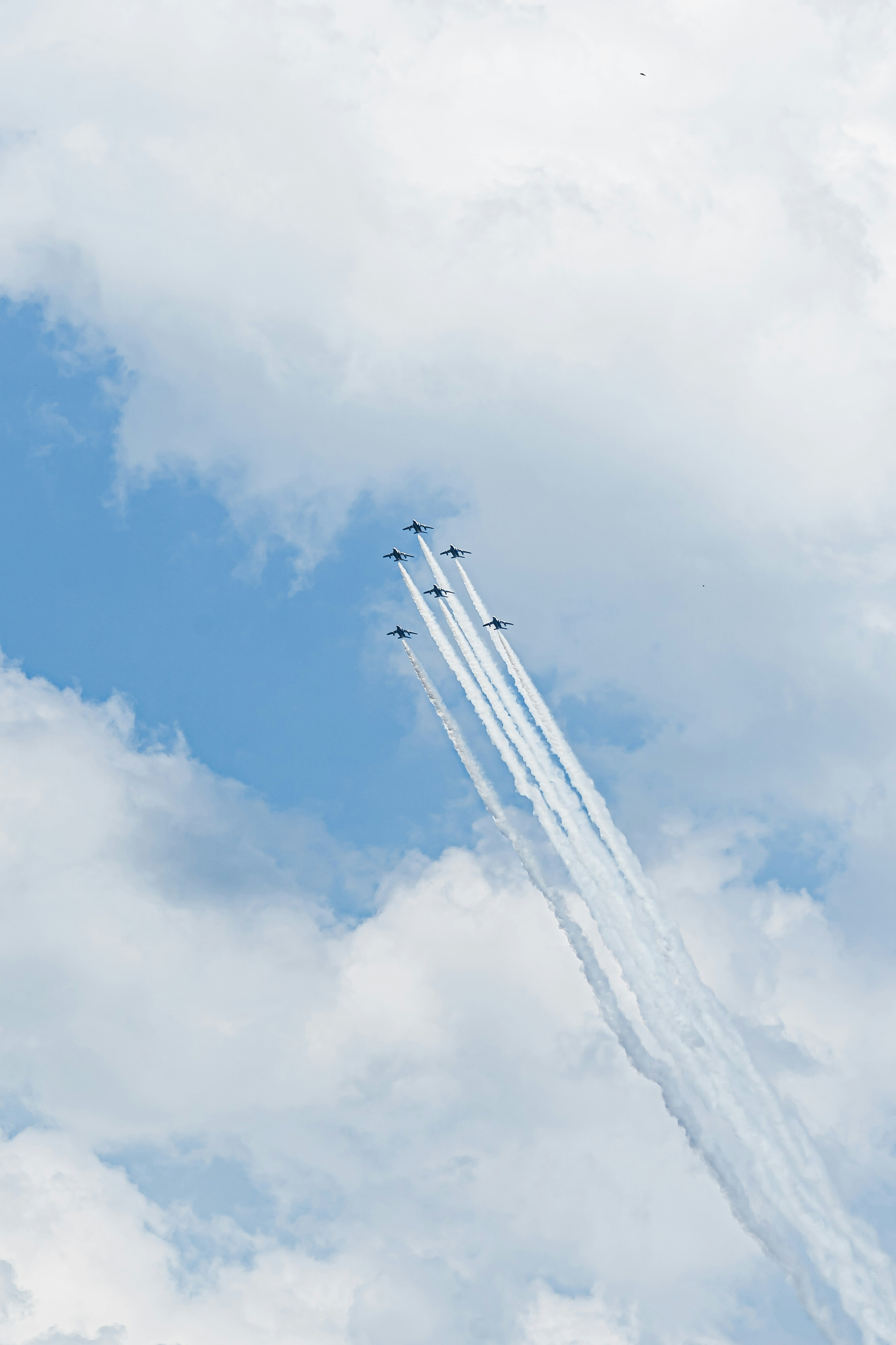 A formation of jet planes leaving white smoke trails in a blue sky