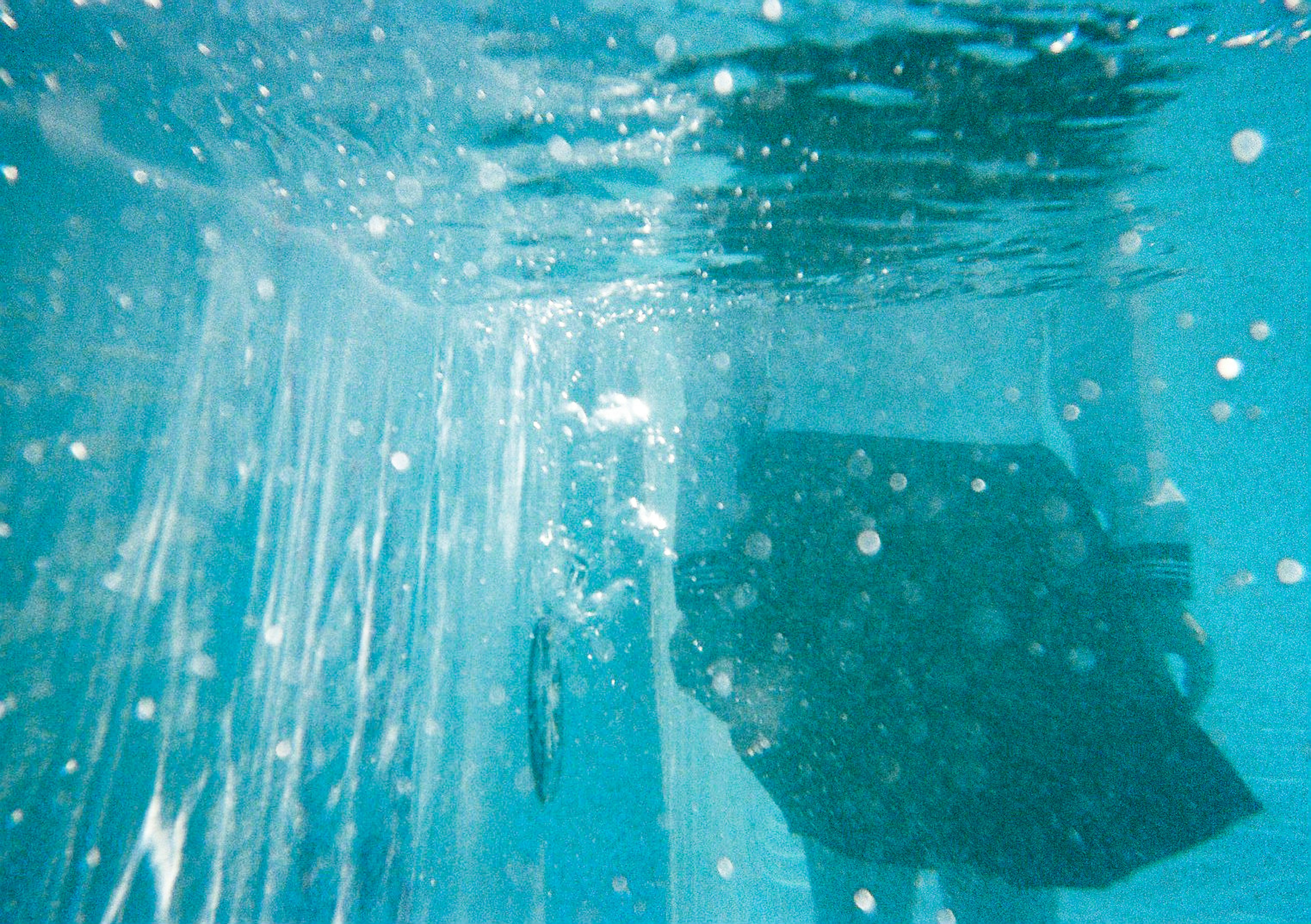 Silhouette d'une personne sous l'eau avec un fond bleu et des bulles