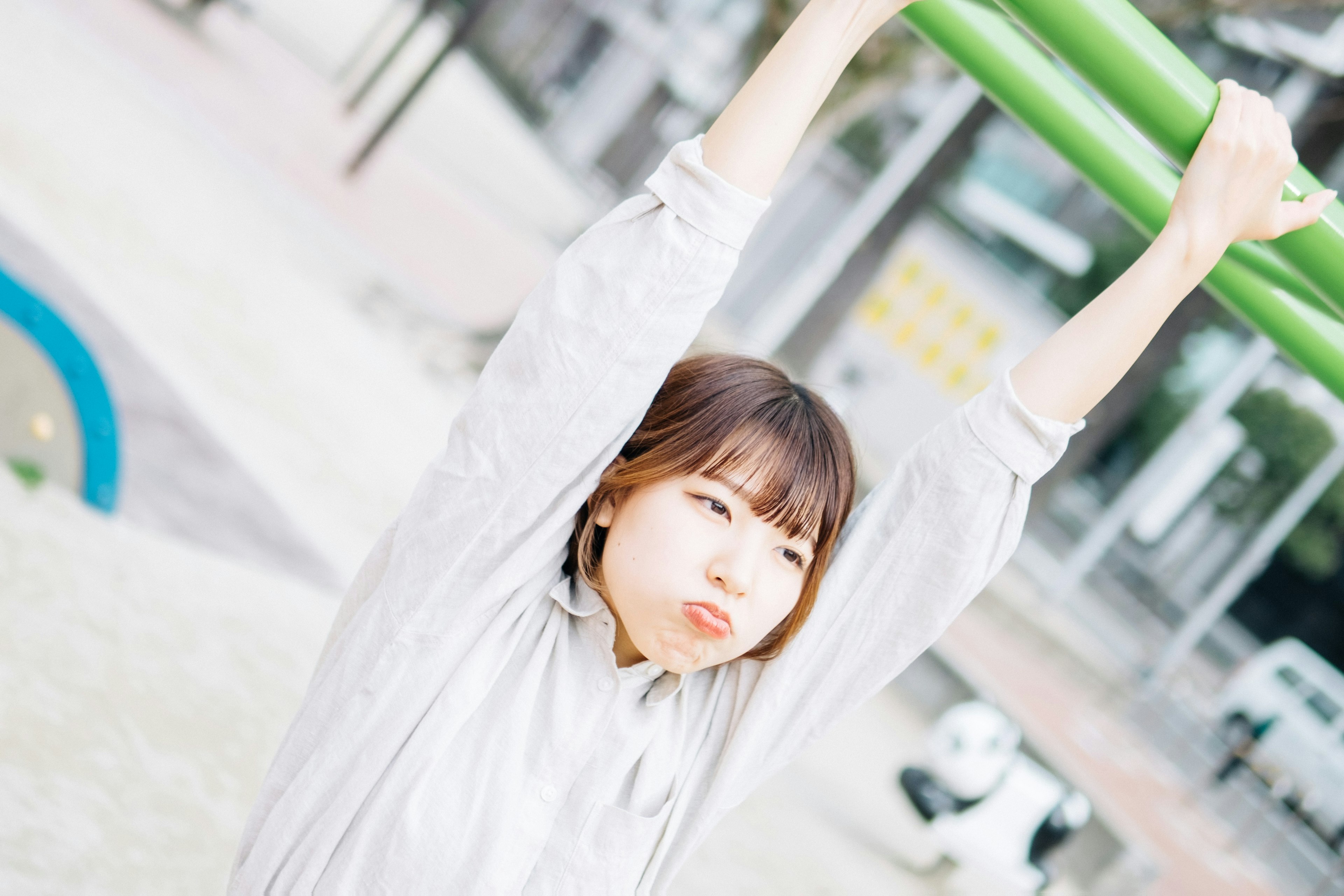 Young woman hanging from a green bar in a park