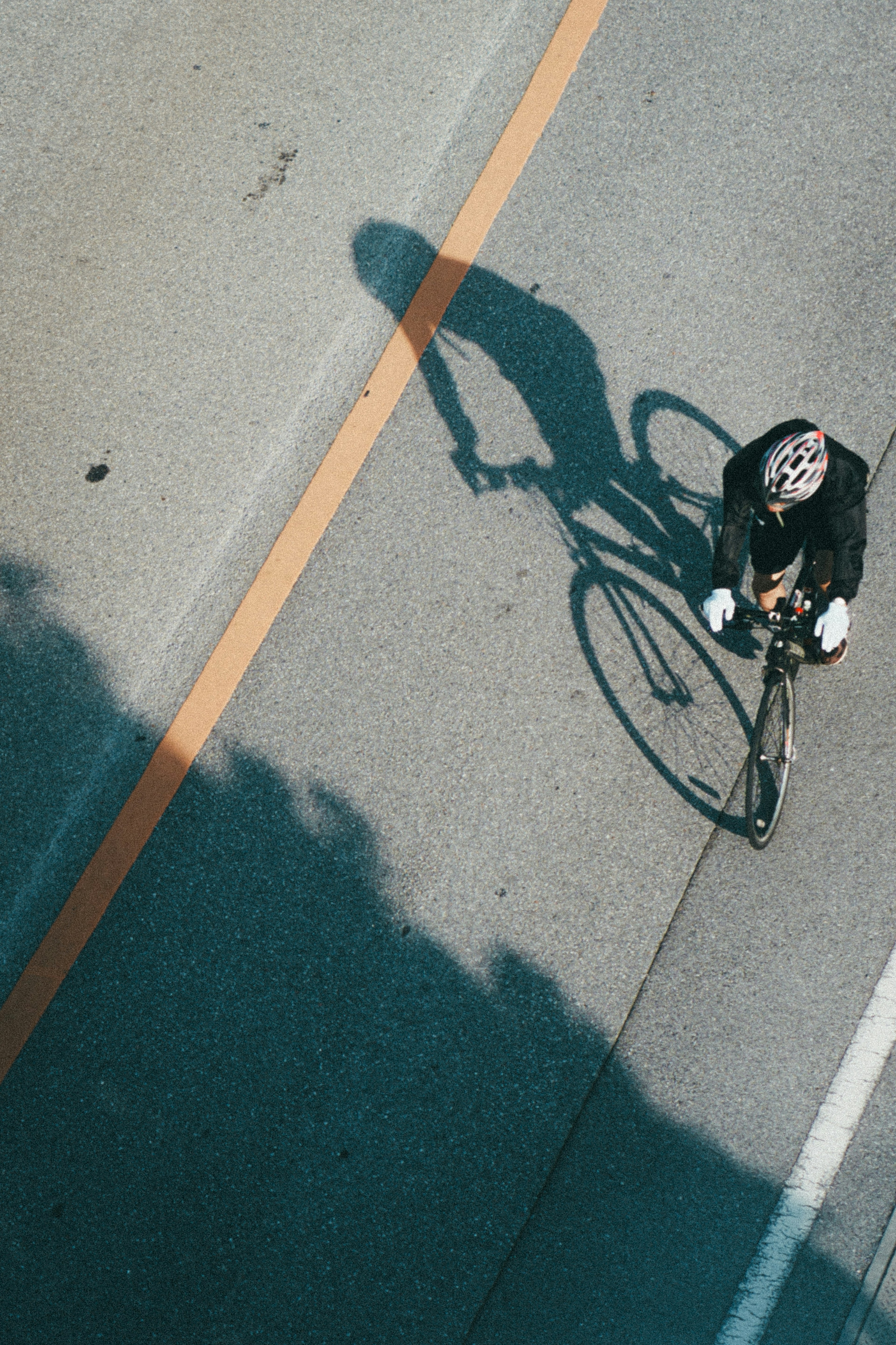 Vista aérea de un ciclista proyectando una sombra en la carretera