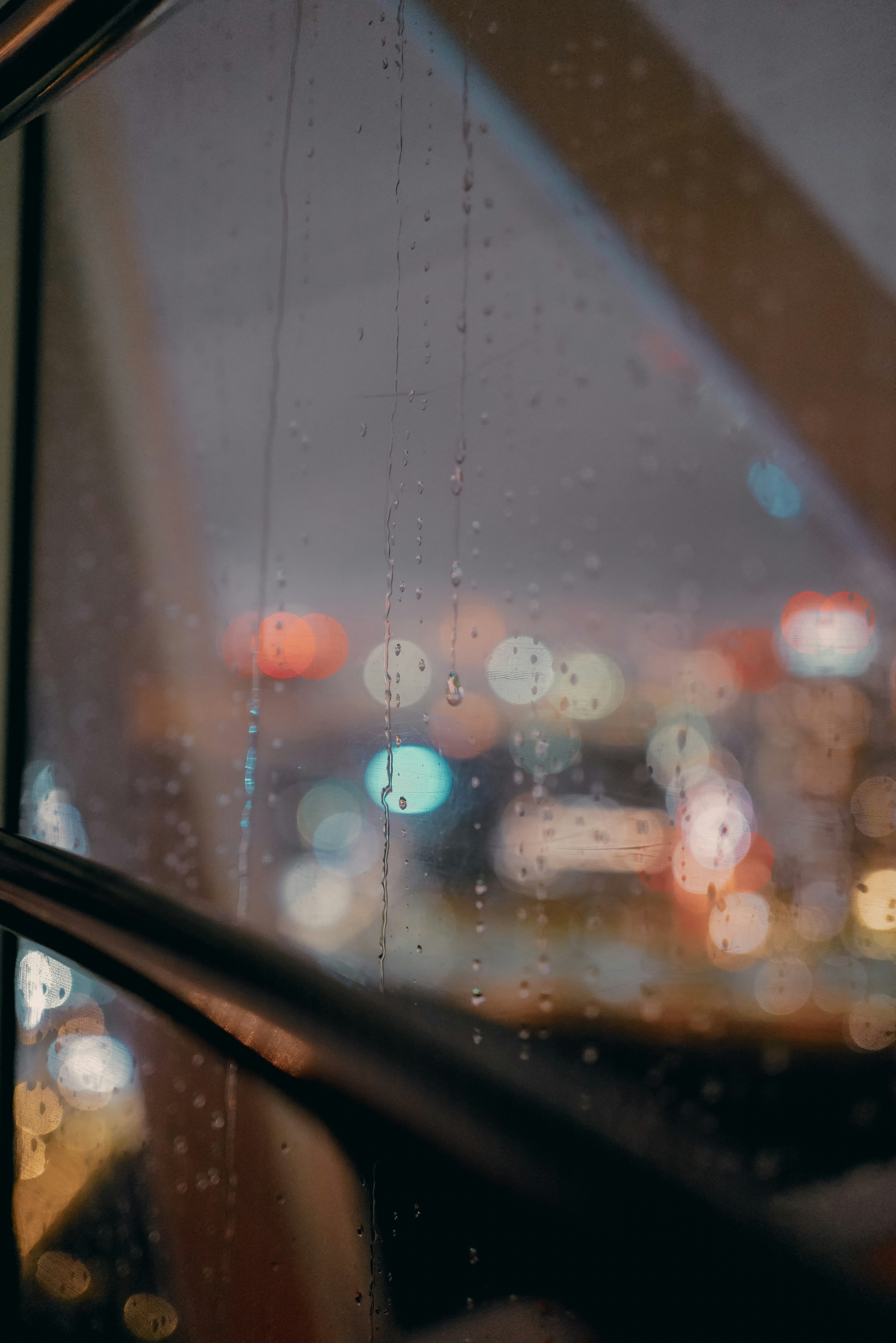 Luces de la ciudad borrosas de noche vistas a través de una ventana con lluvia