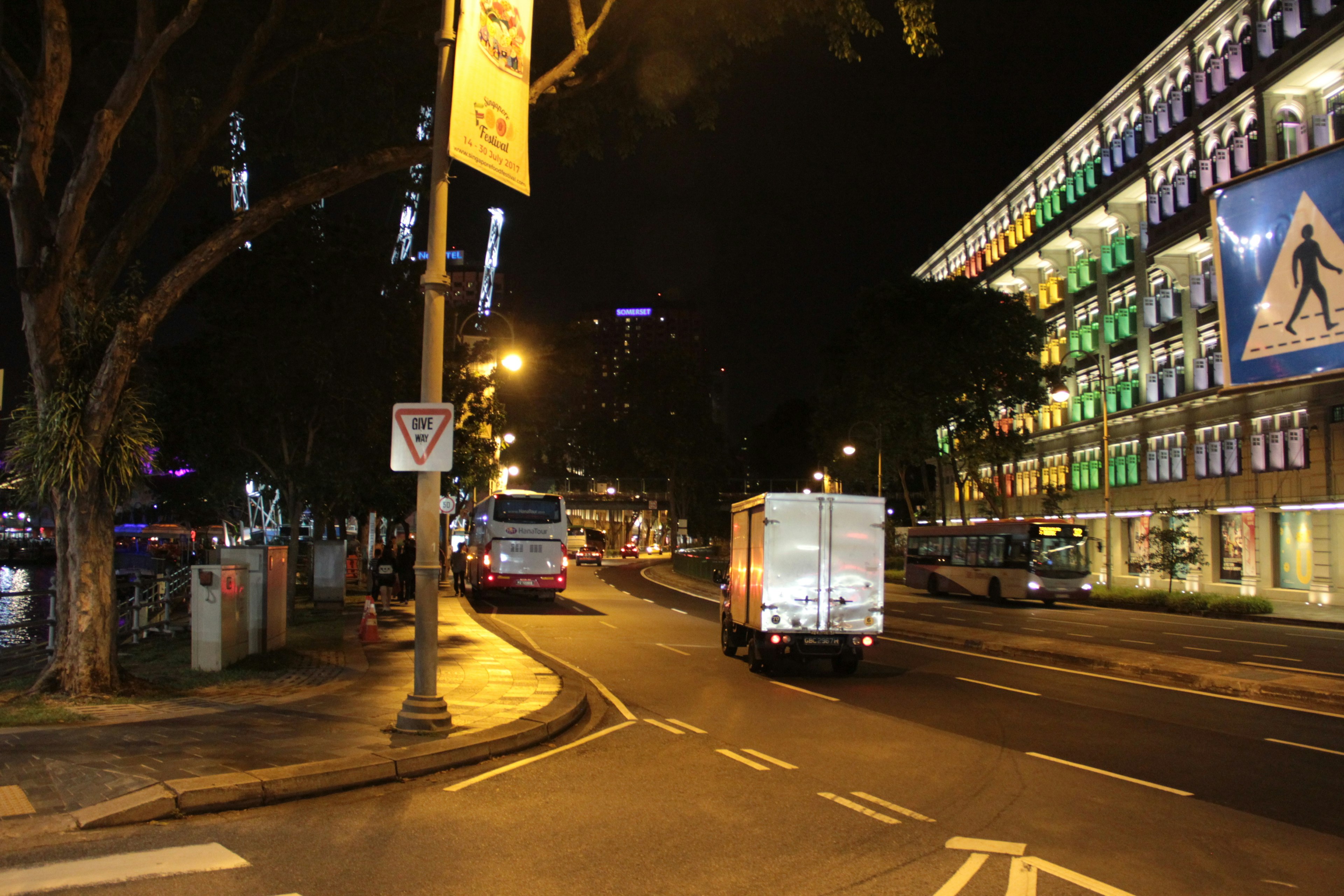 Scène de rue nocturne avec des bâtiments illuminés et des véhicules