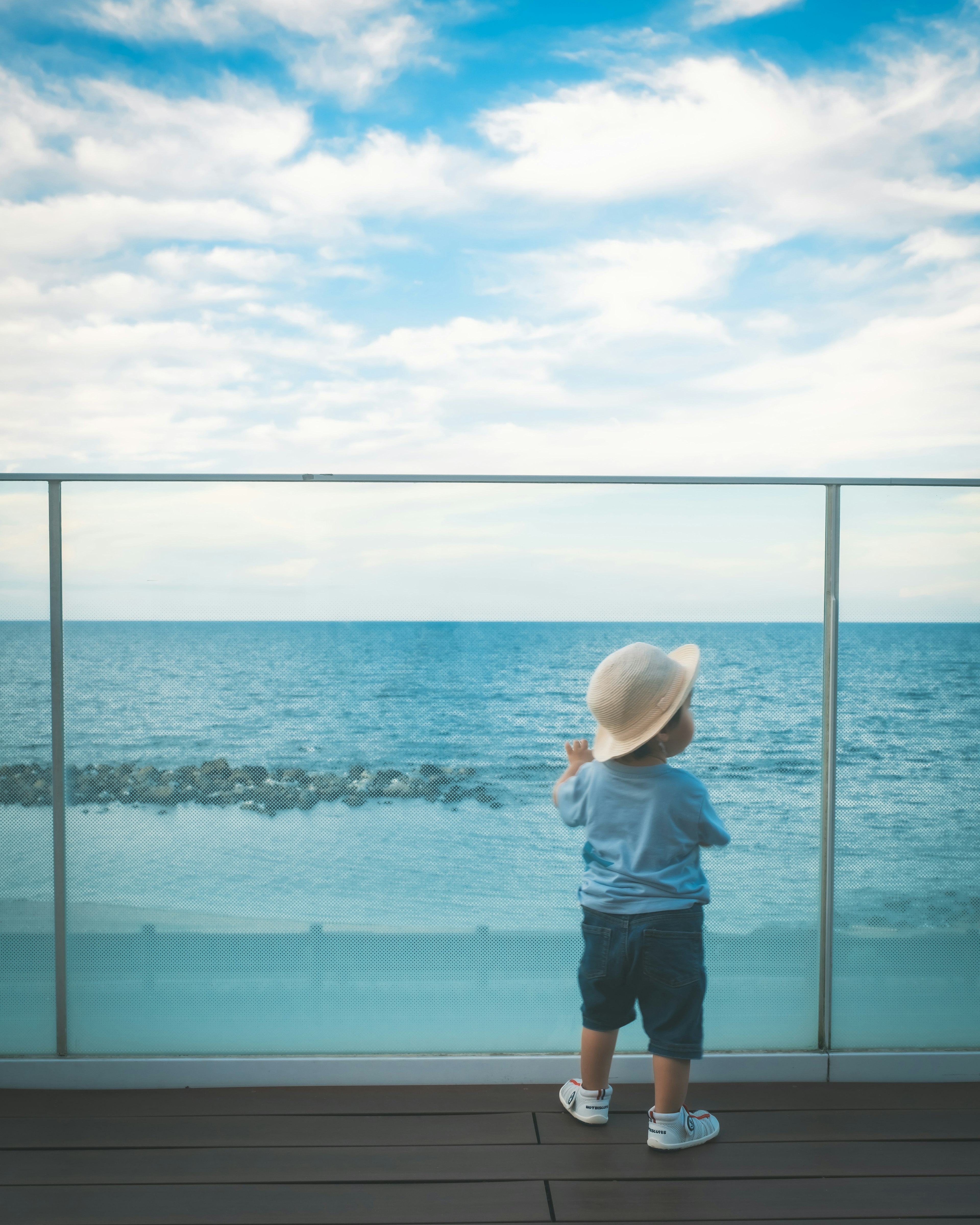 Un bambino che osserva l'oceano da un balcone