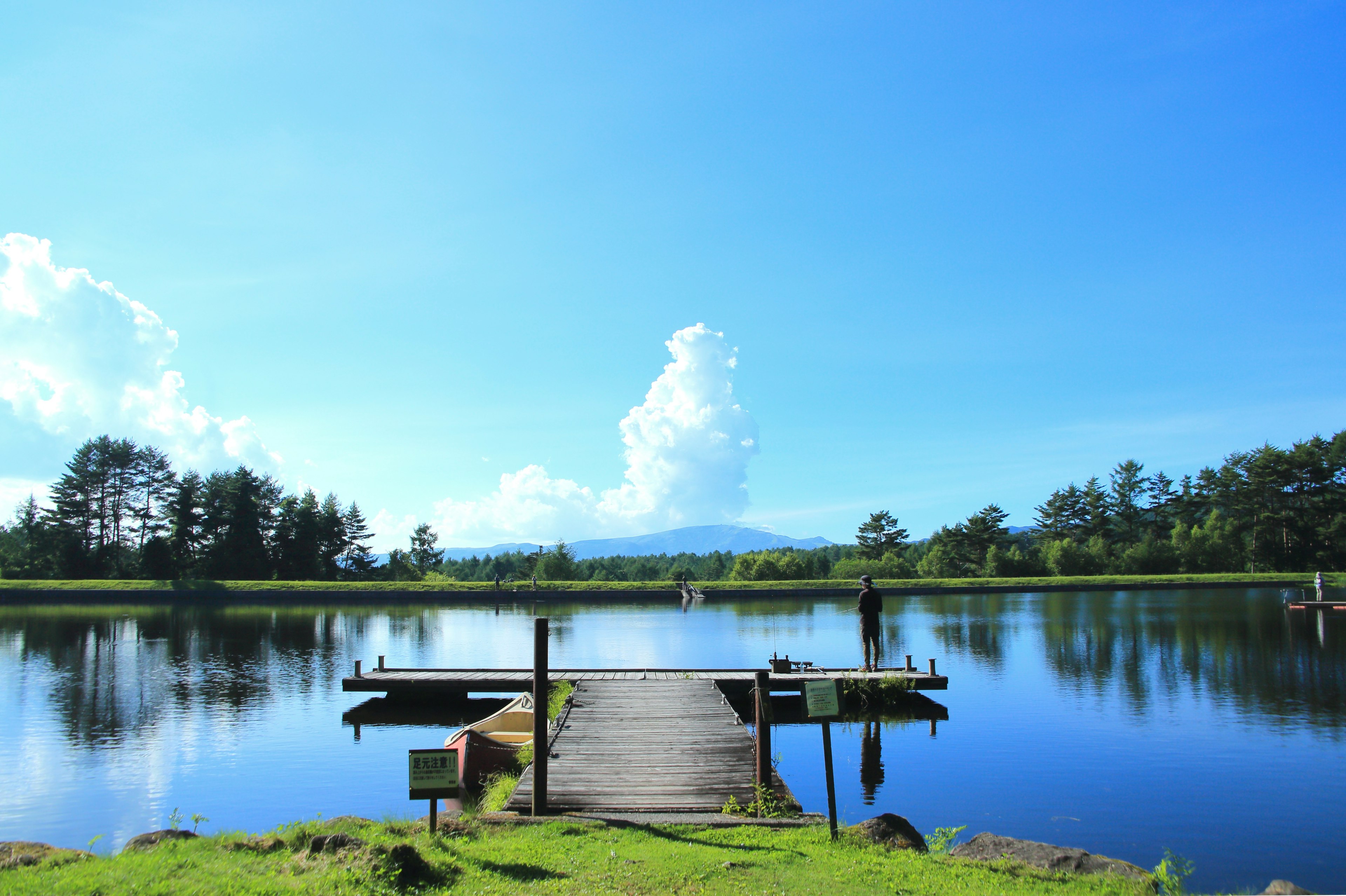 A serene lake under a blue sky with a wooden dock