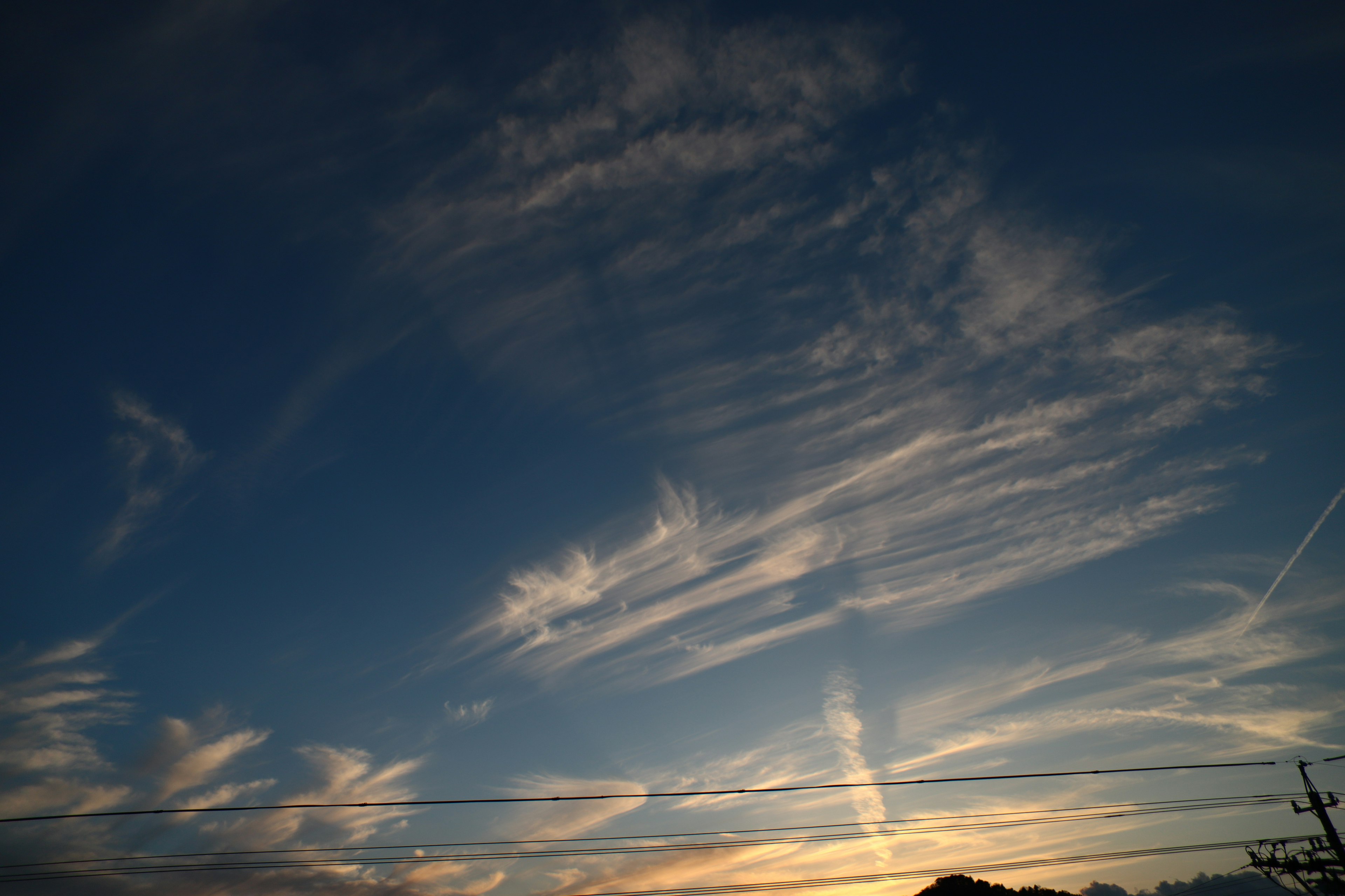 Blauer Himmel mit wirbelnden Wolkenmustern und Licht der Abenddämmerung