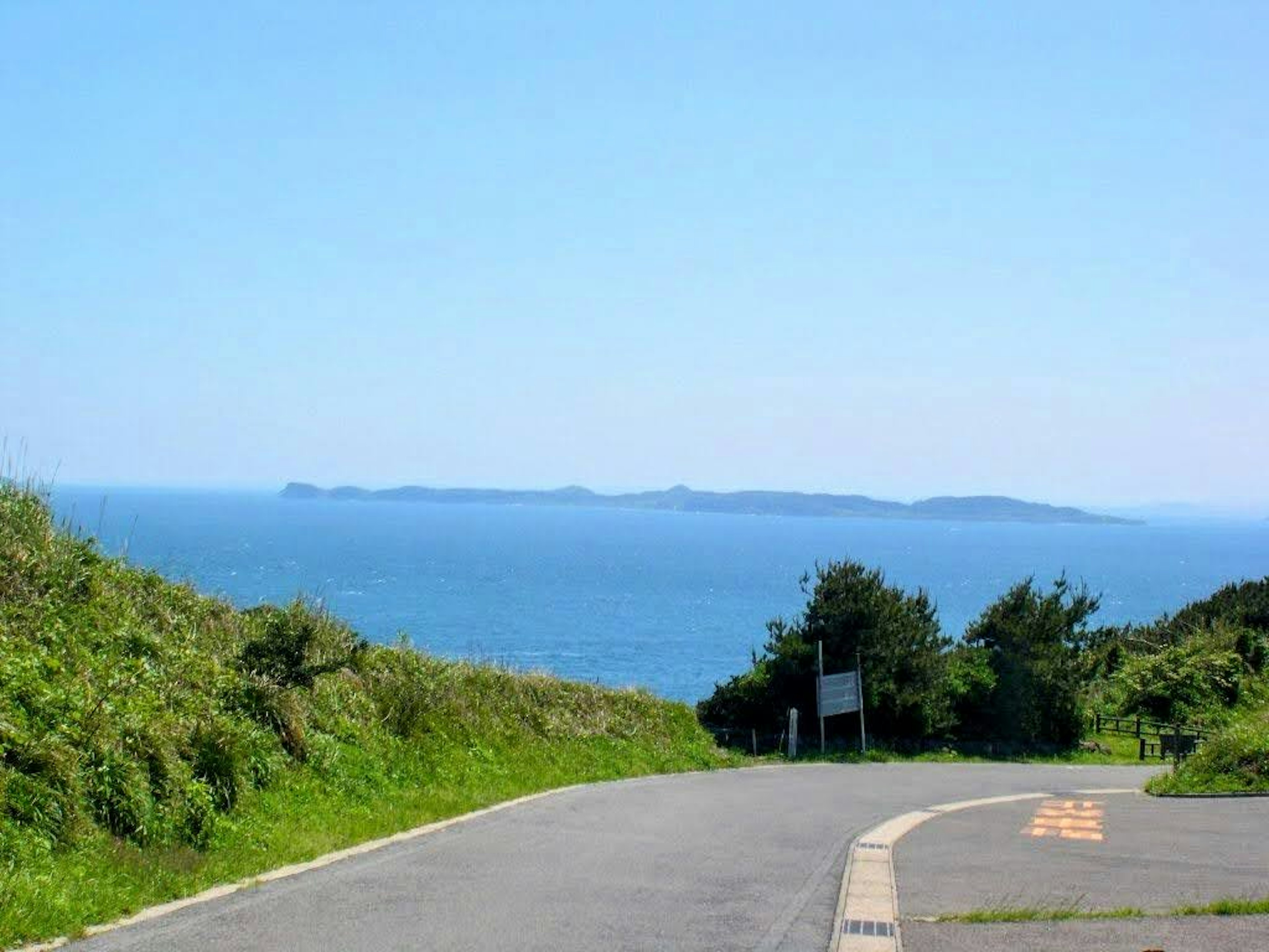 绿意盎然的道路，远处可见蓝色海洋和岛屿