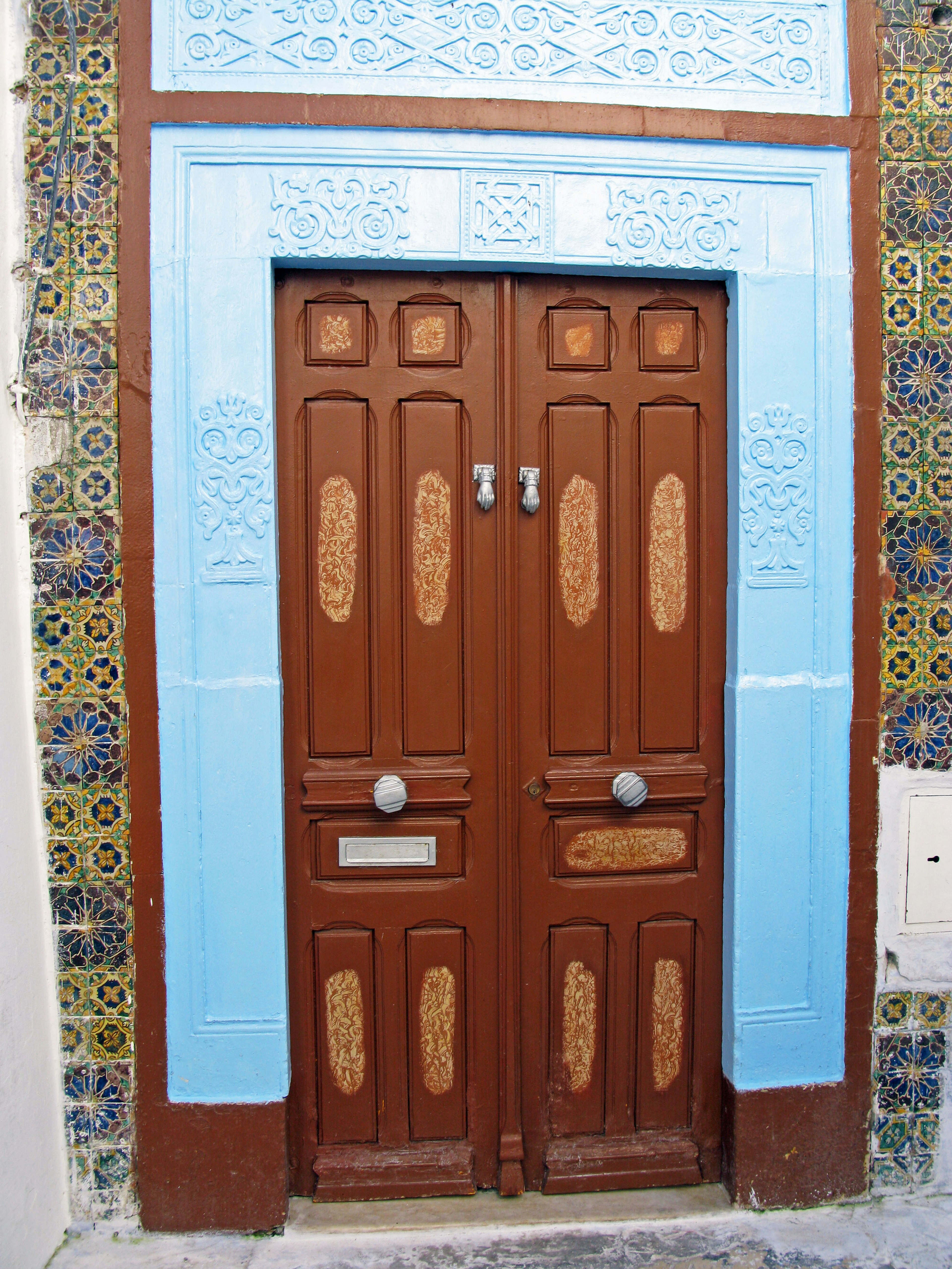 Porta in legno marrone incorniciata di blu con piastrelle decorative