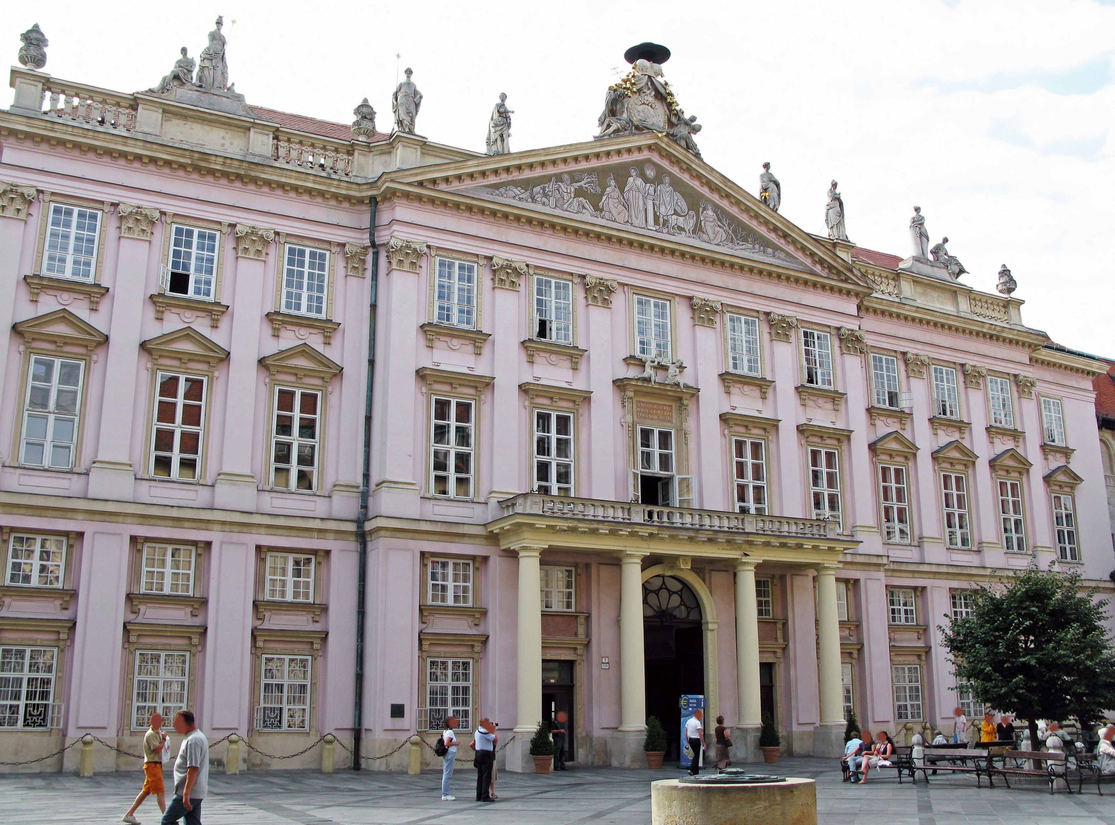 Historic building with a pink facade and people in front