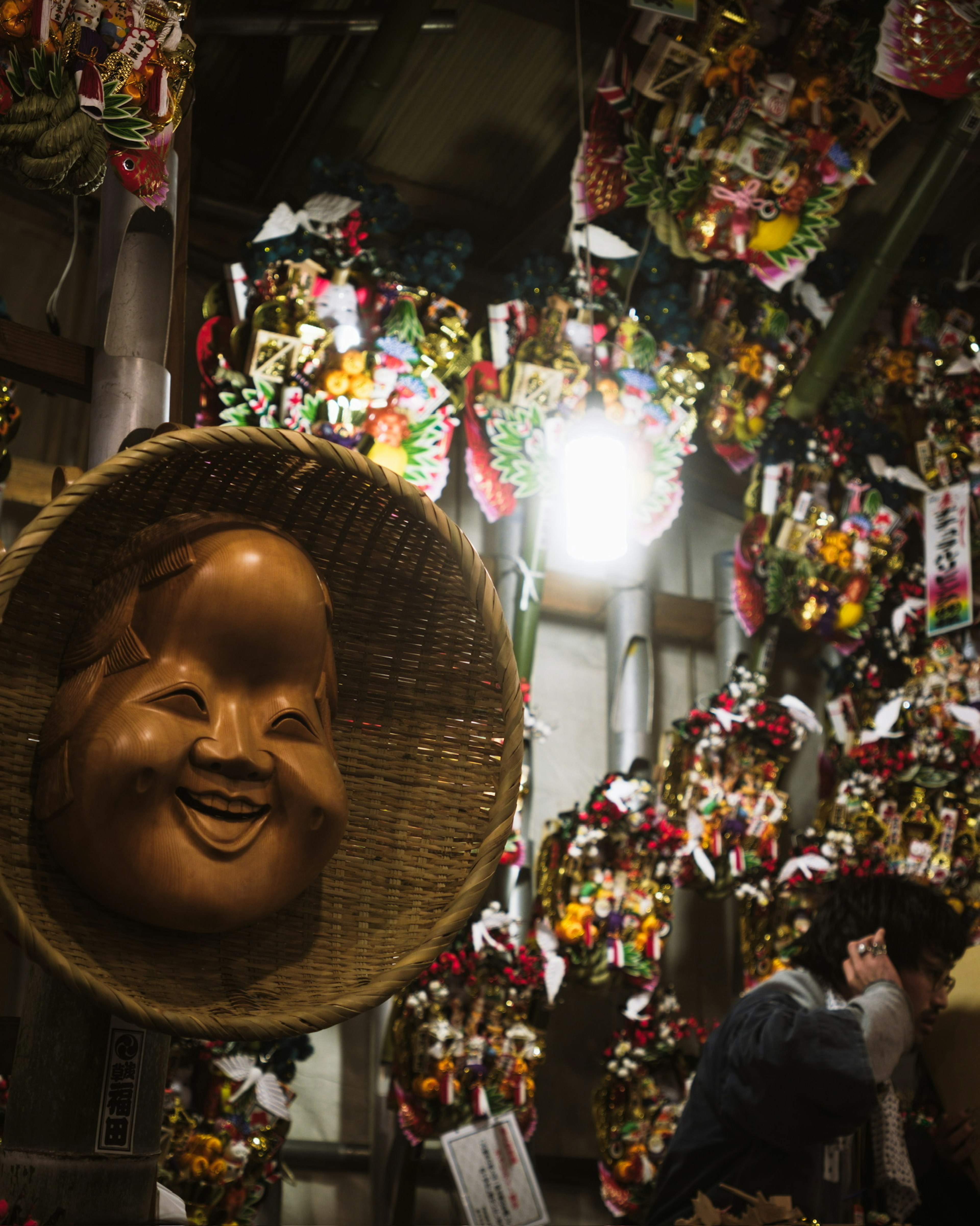 A large smiling sculpture surrounded by colorful decorations and flowers indoors