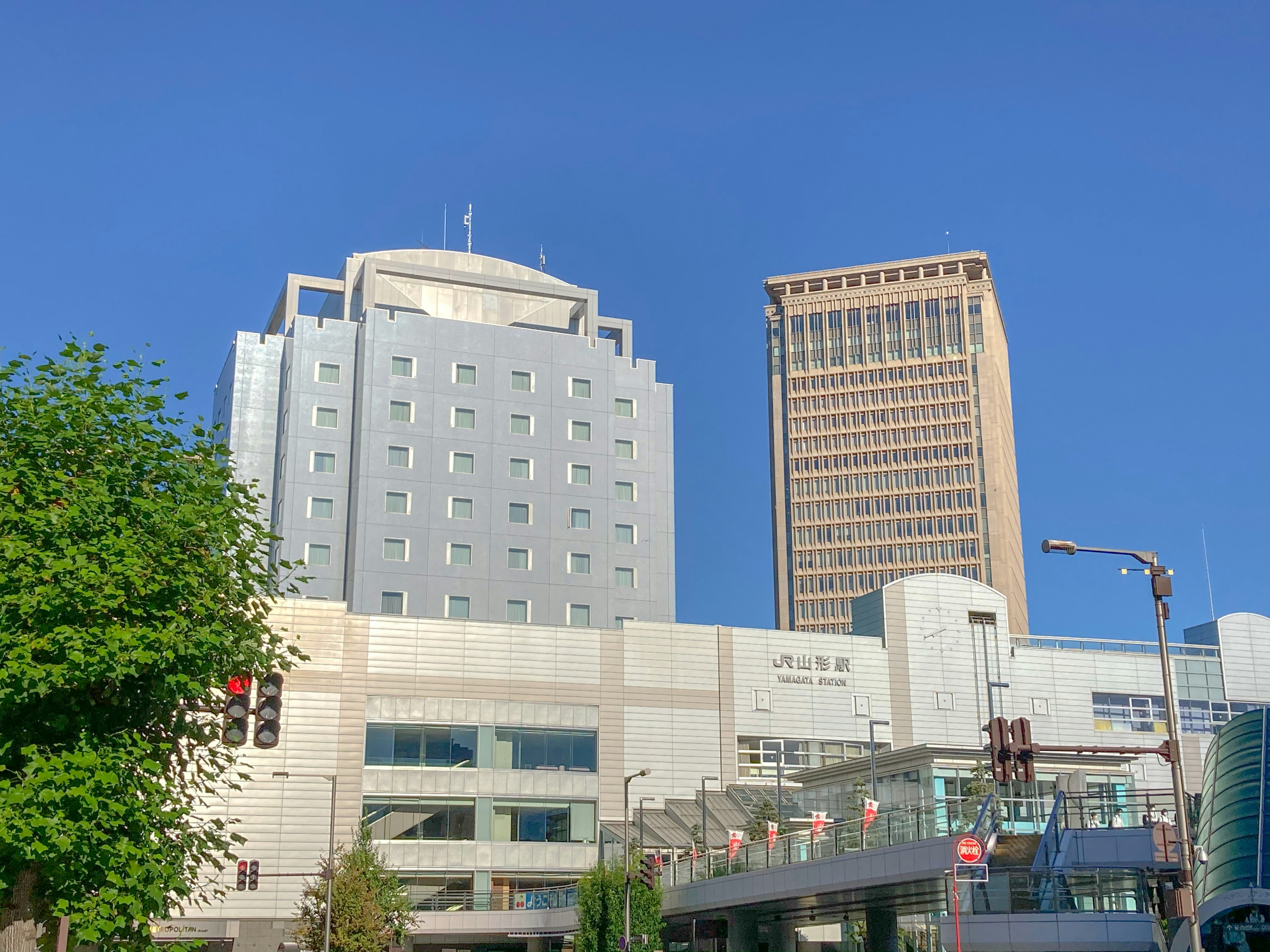 青空の下に立つ現代的なビルと商業施設の風景