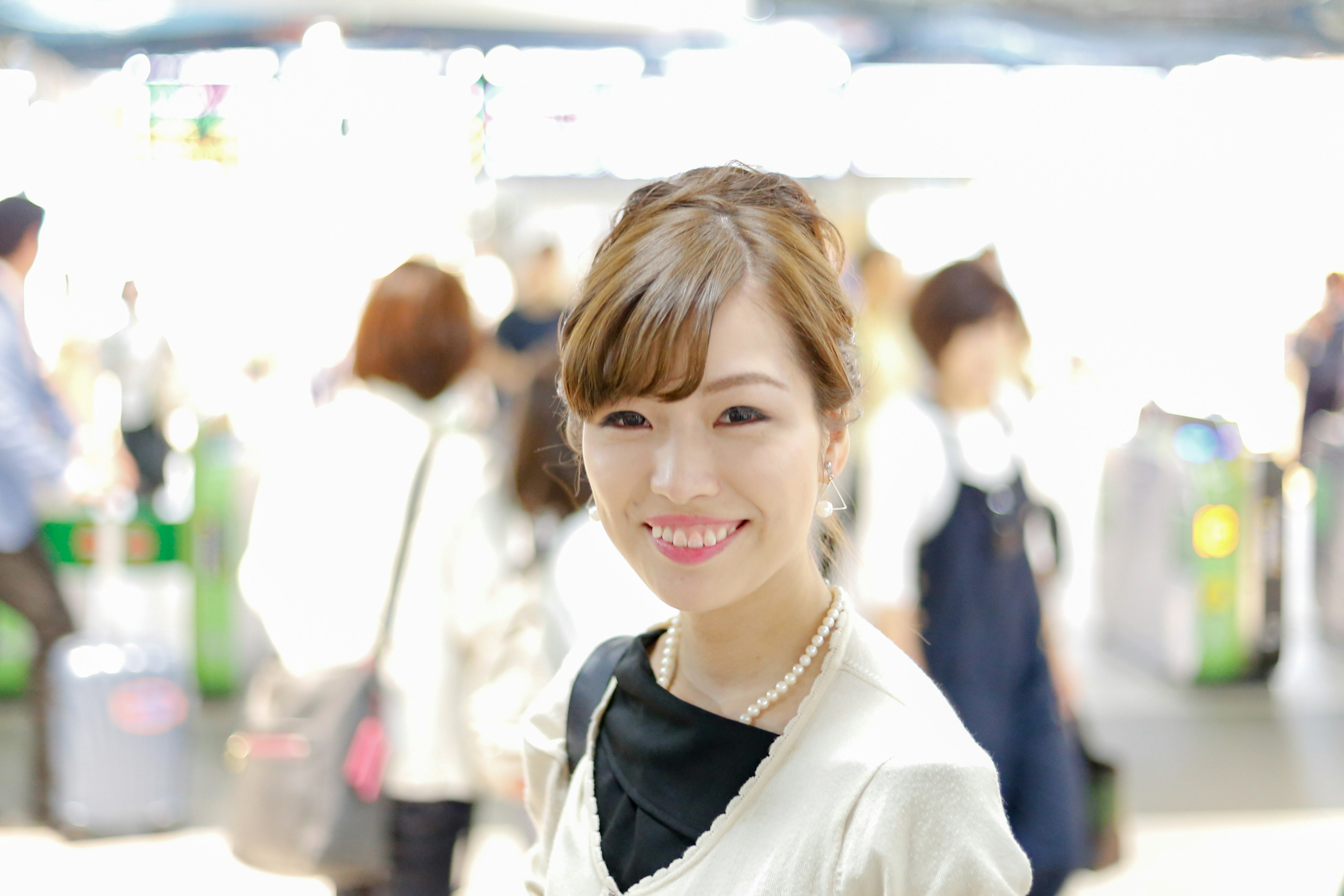 Portrait of a smiling woman with a bright background She is wearing a white jacket and has brown shoulder-length hair