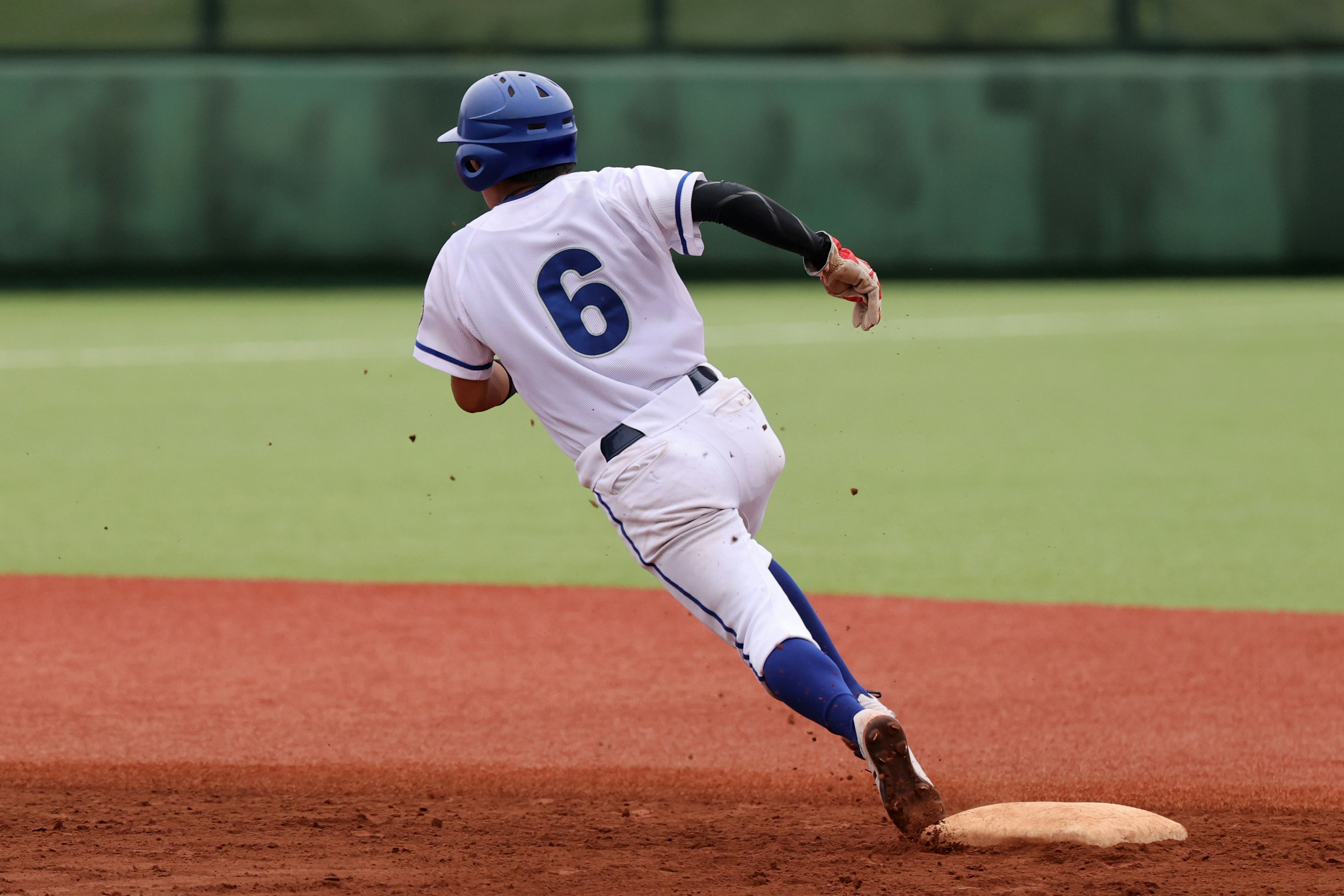 Jugador de béisbol corriendo hacia la segunda base con el número 6