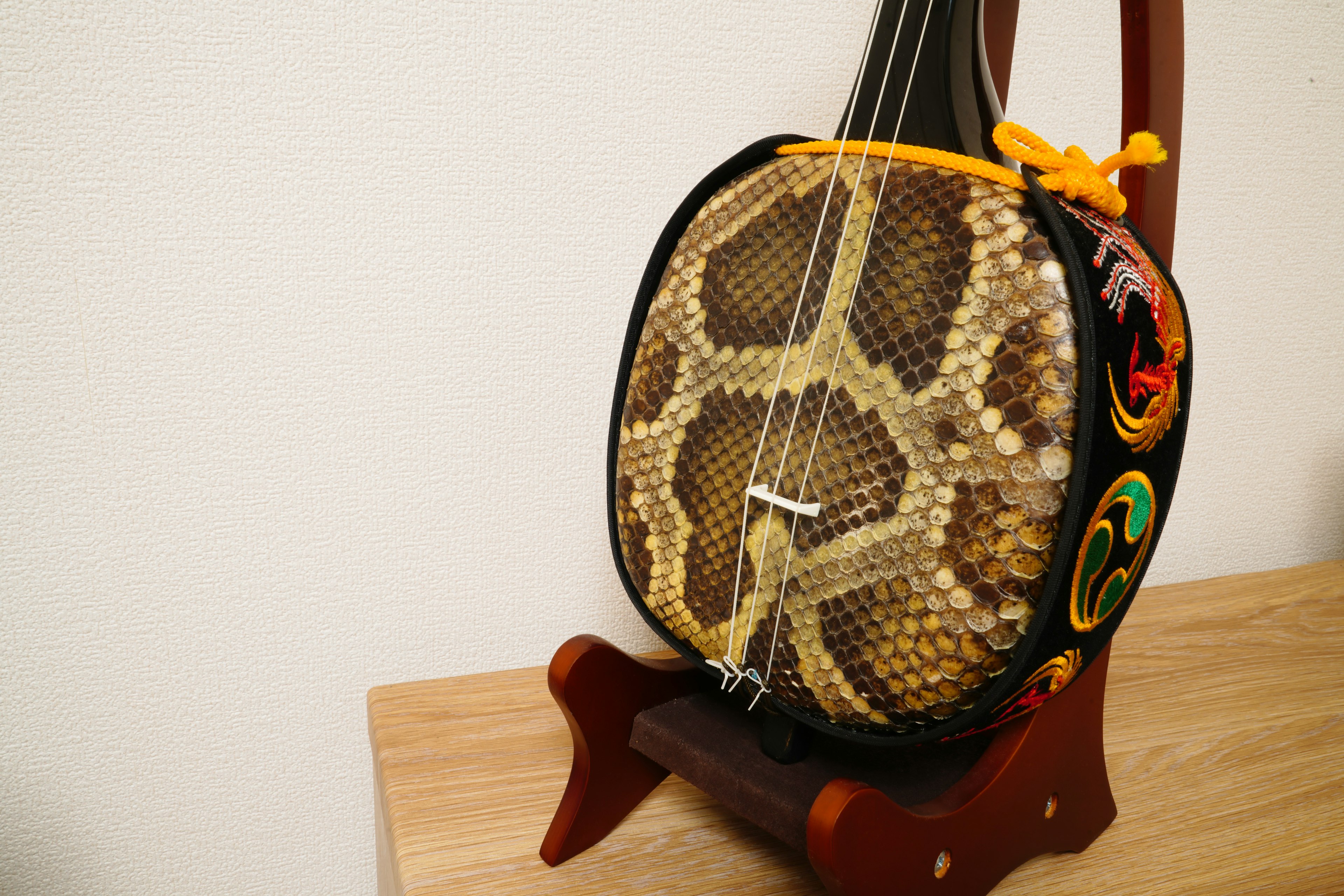 A unique instrument featuring a snake skin banjo displayed on a wooden stand