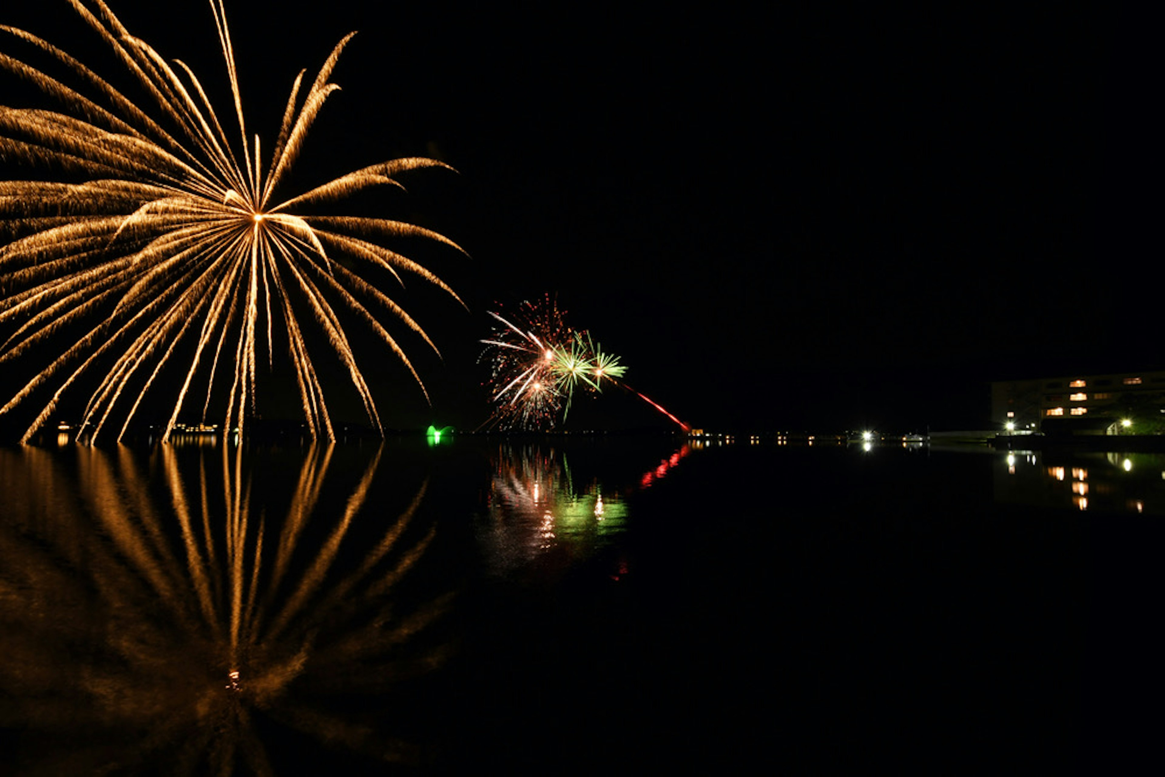 Beautiful fireworks display in the night sky with reflections on the water