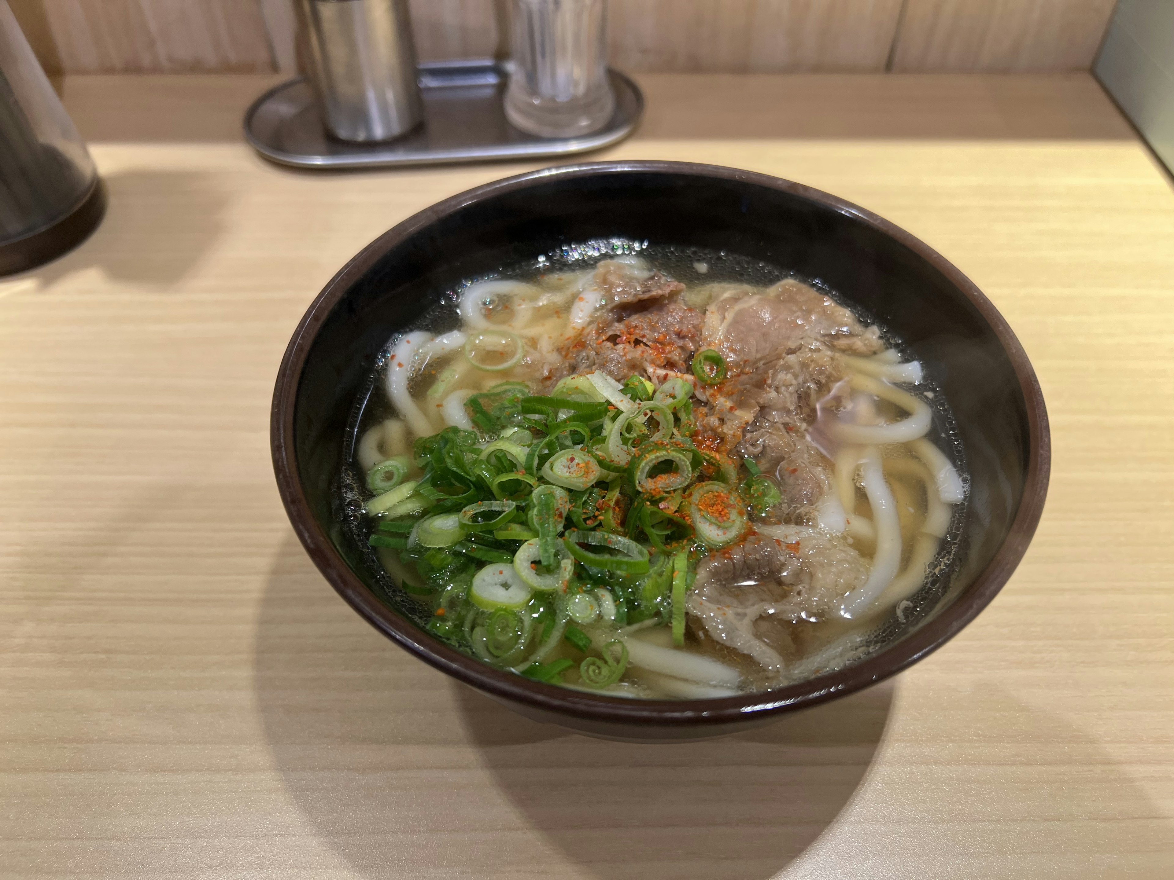 Sup udon dalam mangkuk hitam dengan daging sapi dan bawang hijau