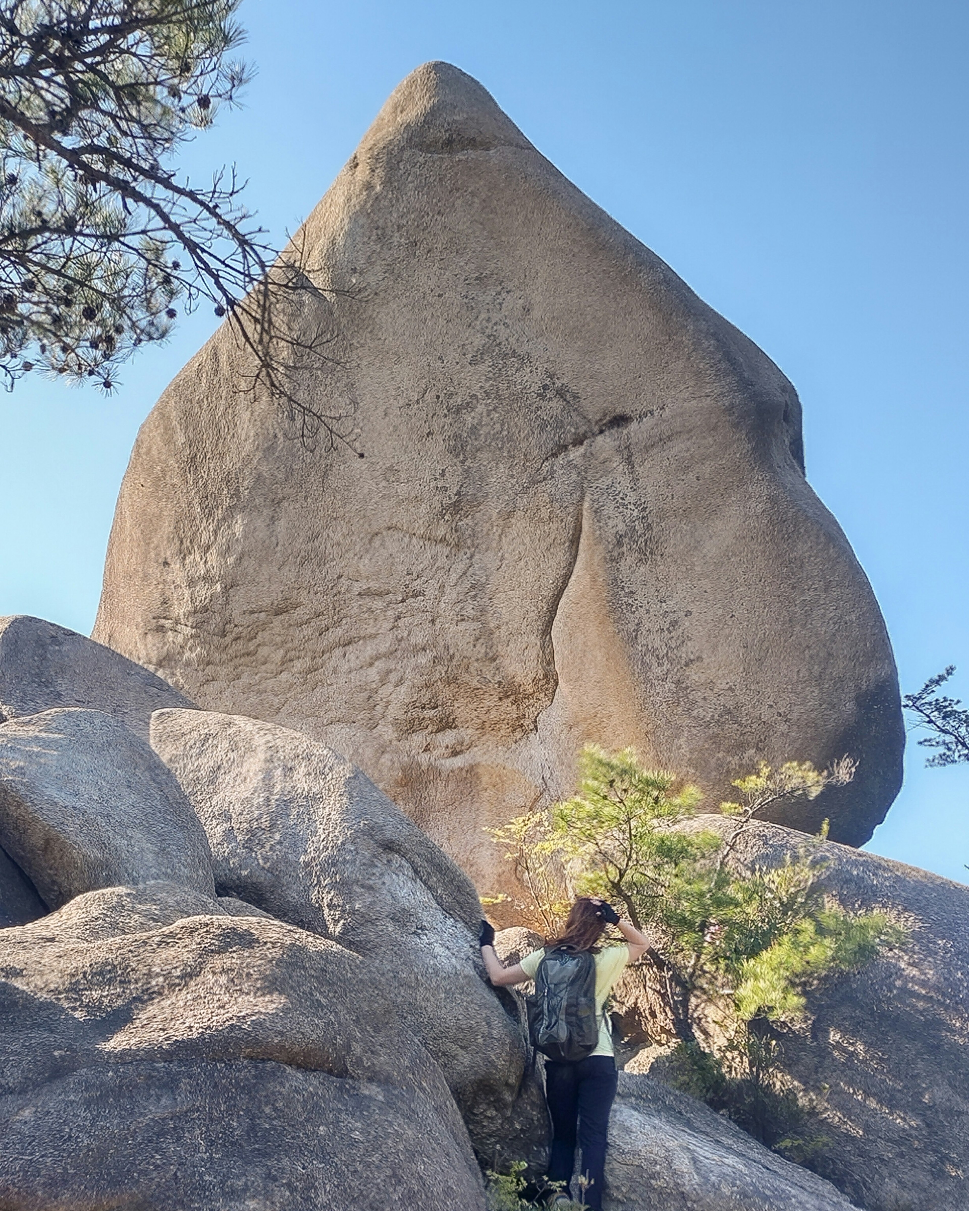 Persona de pie frente a un gran bloque de piedra con rocas circundantes