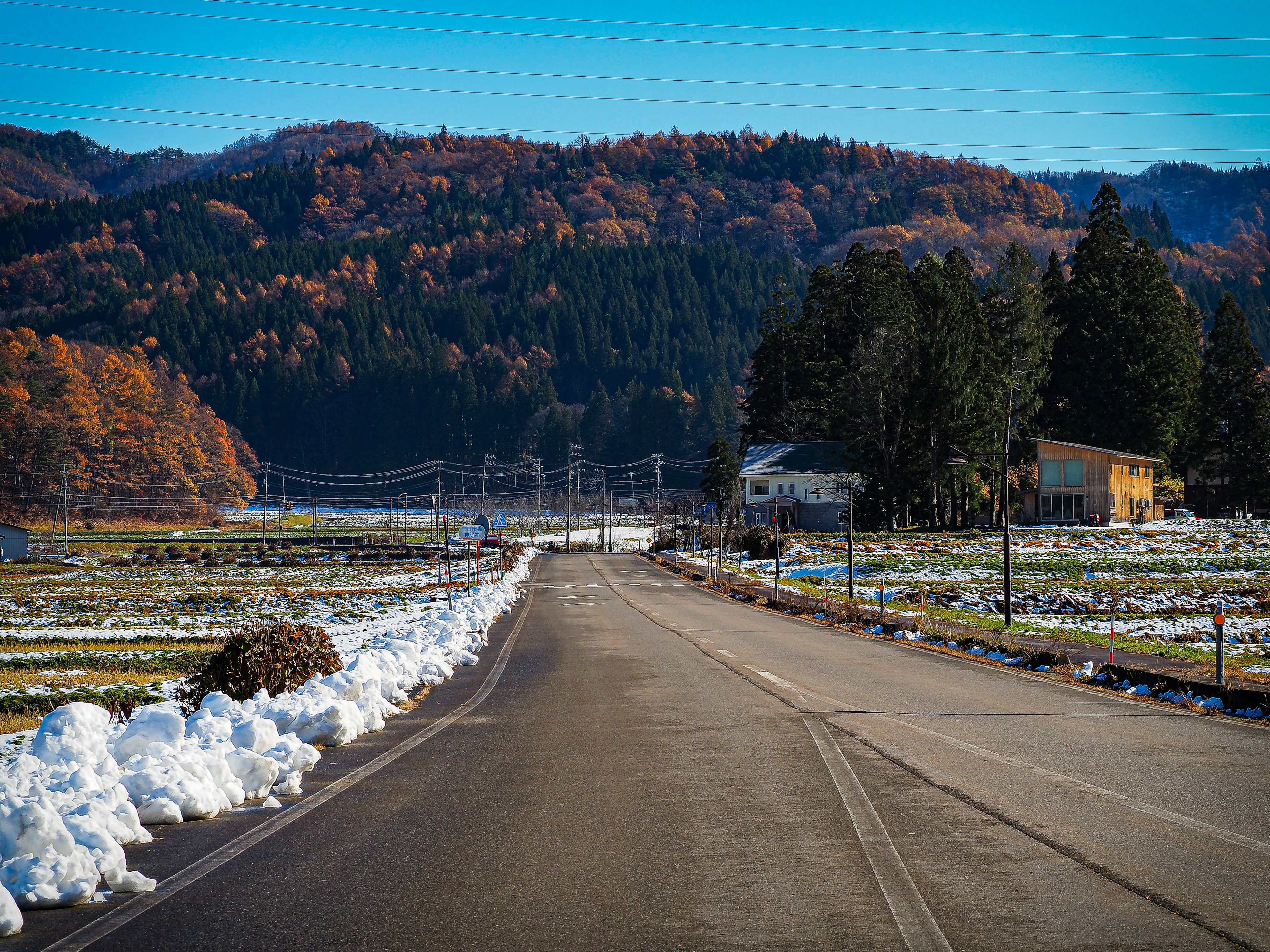 雪覆蓋的道路和背景中的秋季山脈