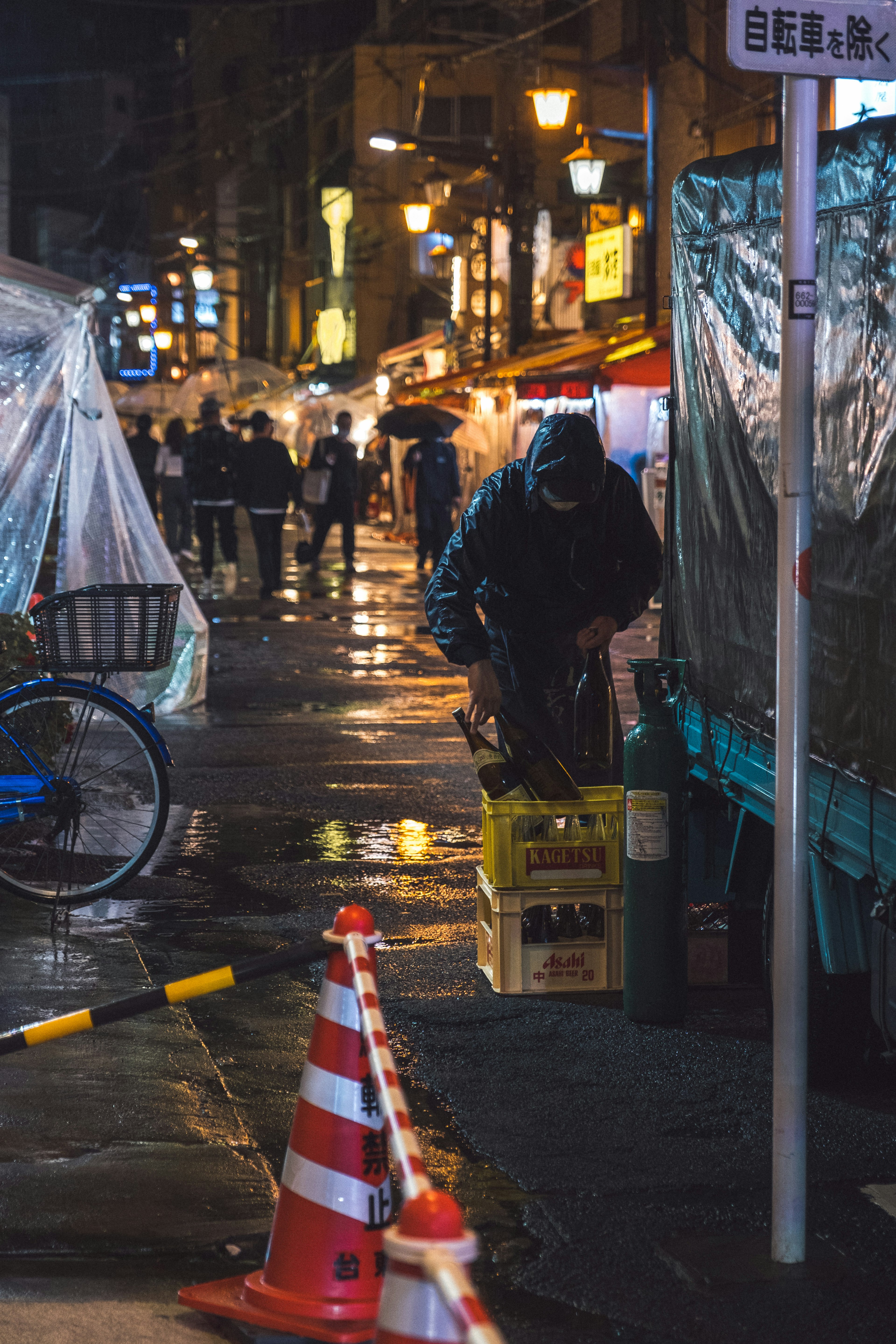 夜市场景，人们在湿漉漉的街道上走，灯光反射