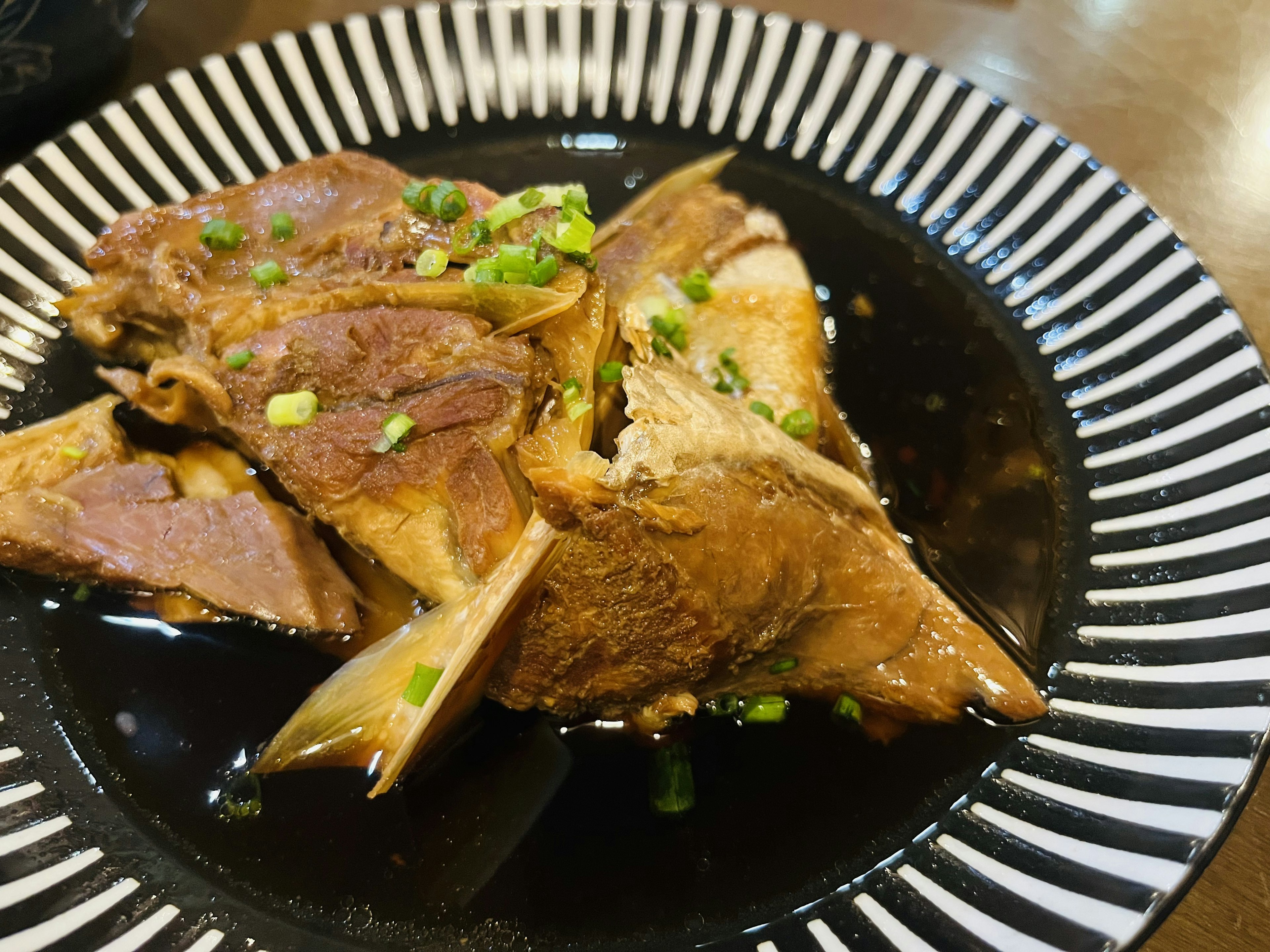 검은 접시에 담긴 맛있는 고기 요리와 쪽파 고명