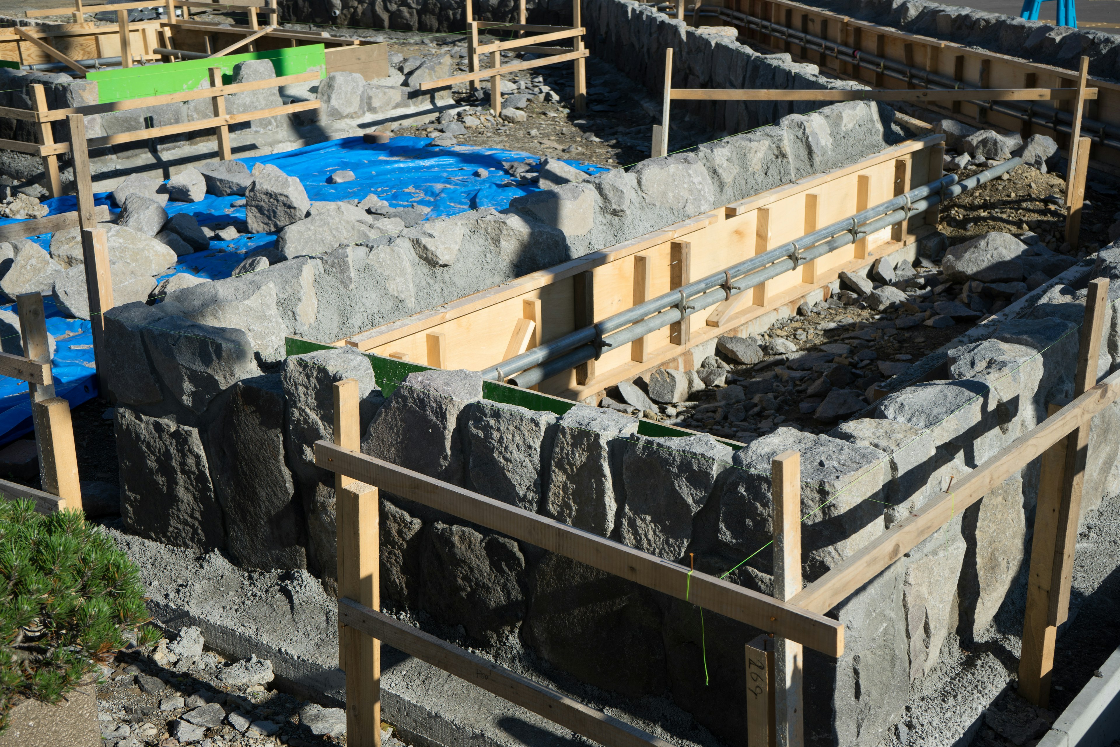 Sitio de construcción con muros de piedra y estructura de madera