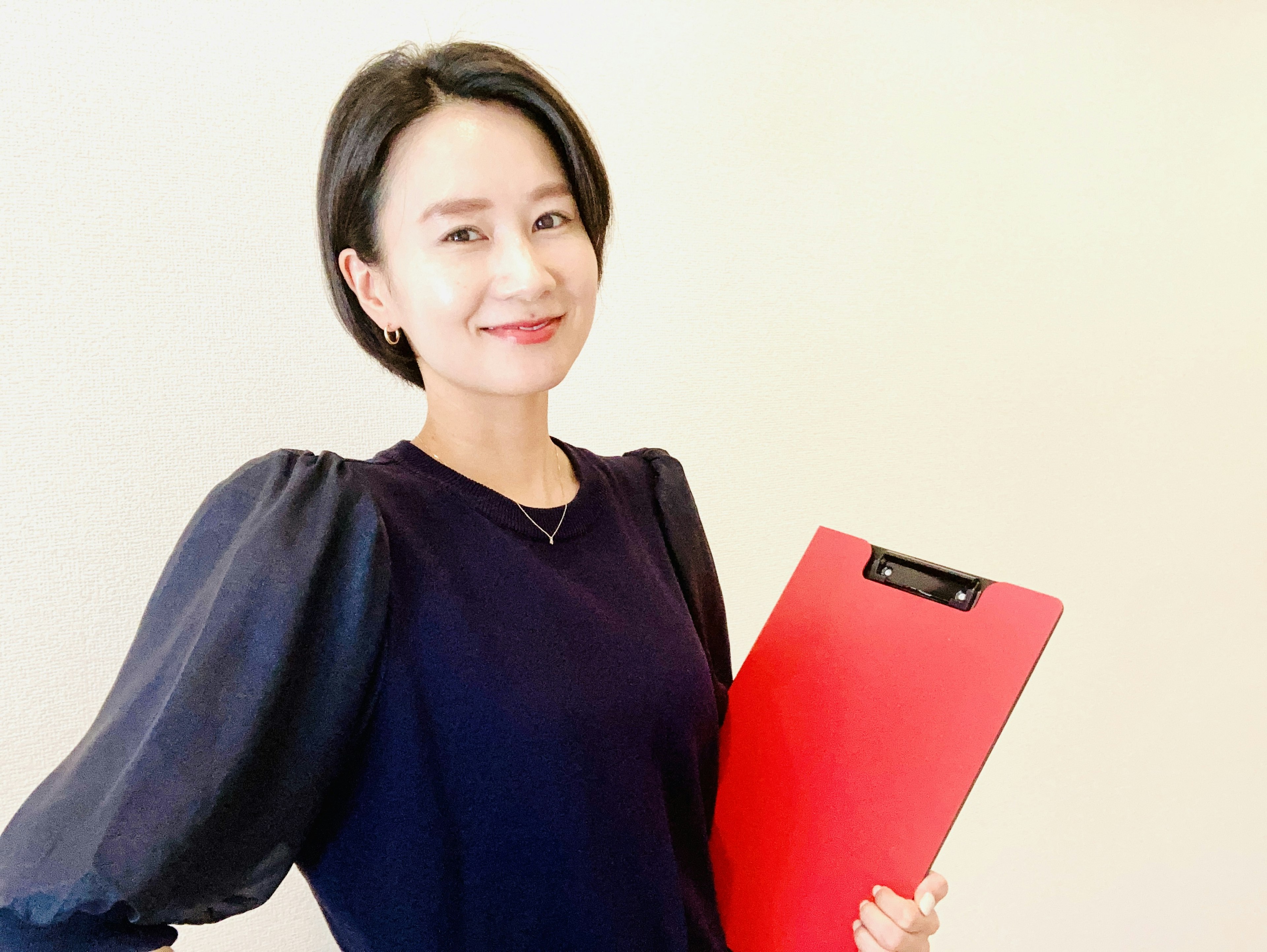 A smiling woman holding a red clipboard