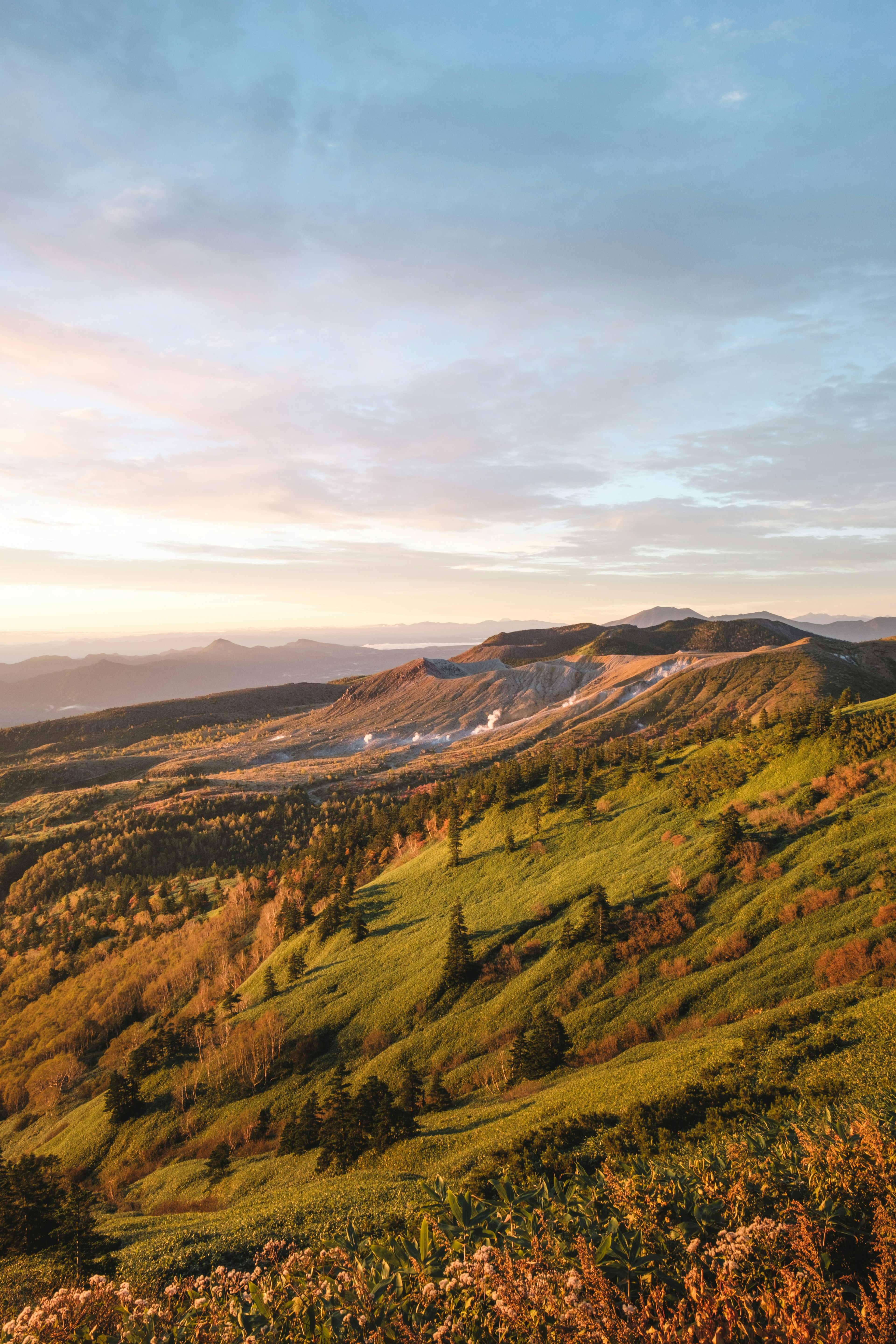 Panorama di colline verdi e montagne illuminate dal tramonto