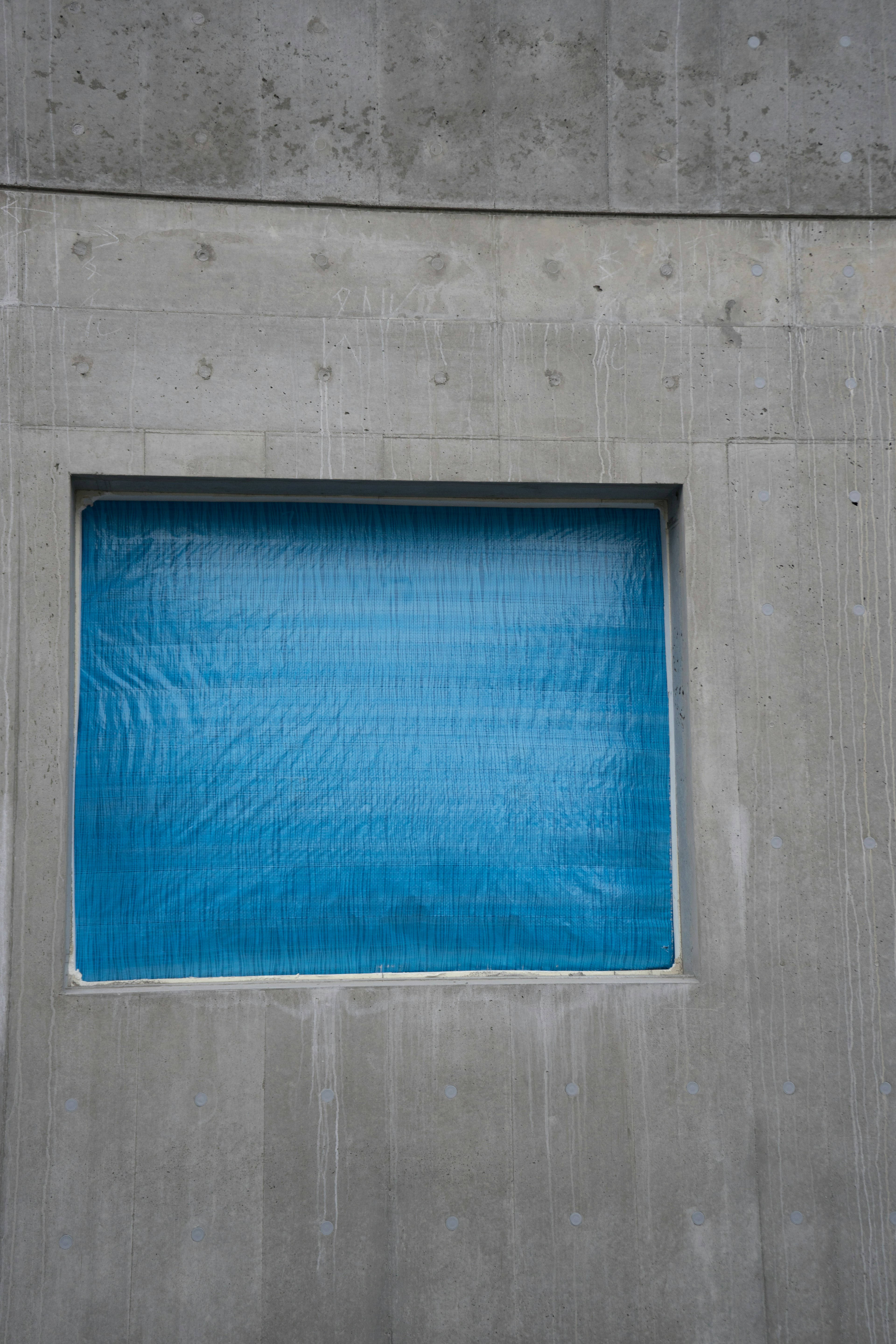 Detail of a blue window set in a concrete wall