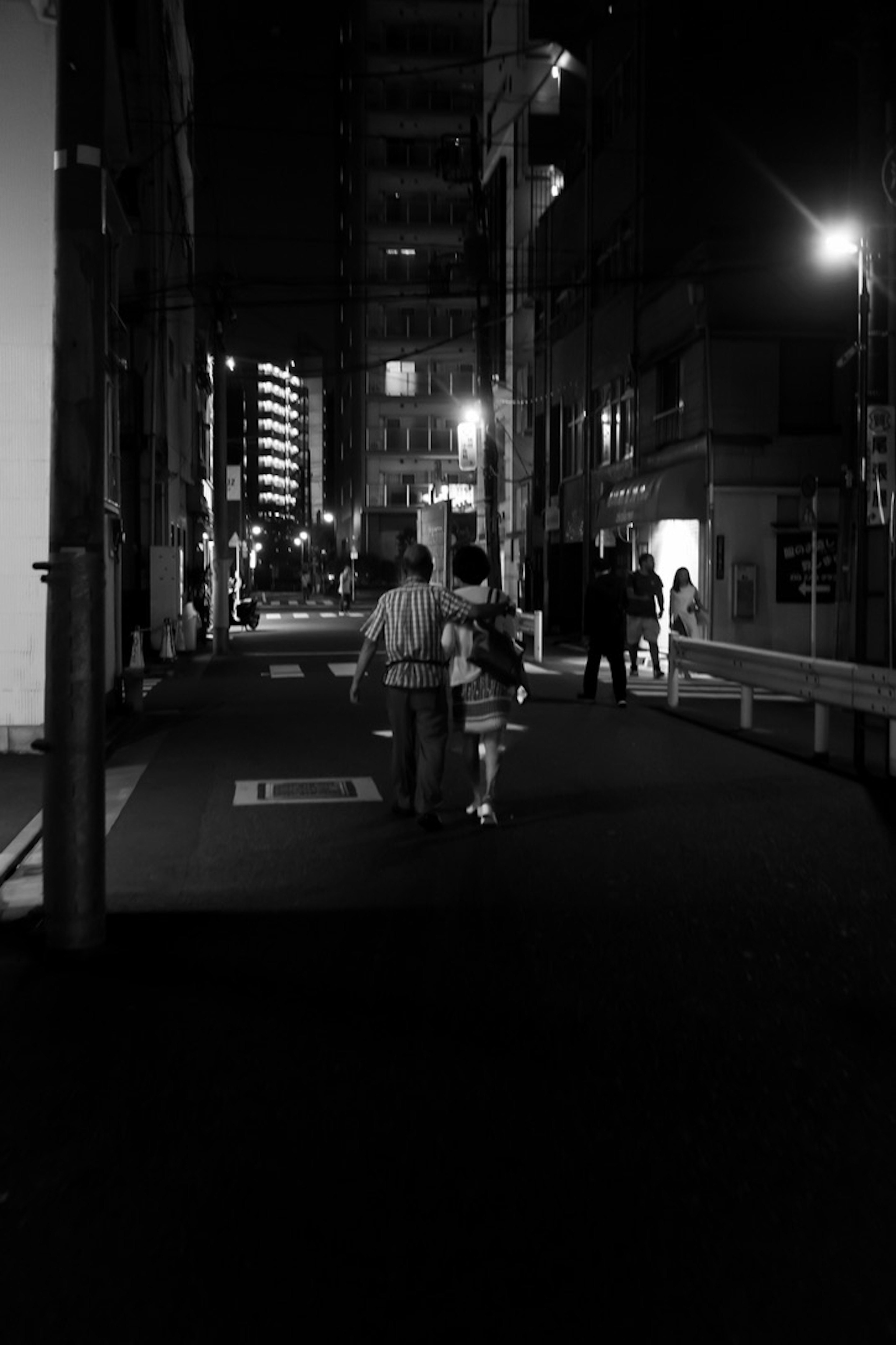 Silhouette of a couple walking in a street at night with surrounding lights