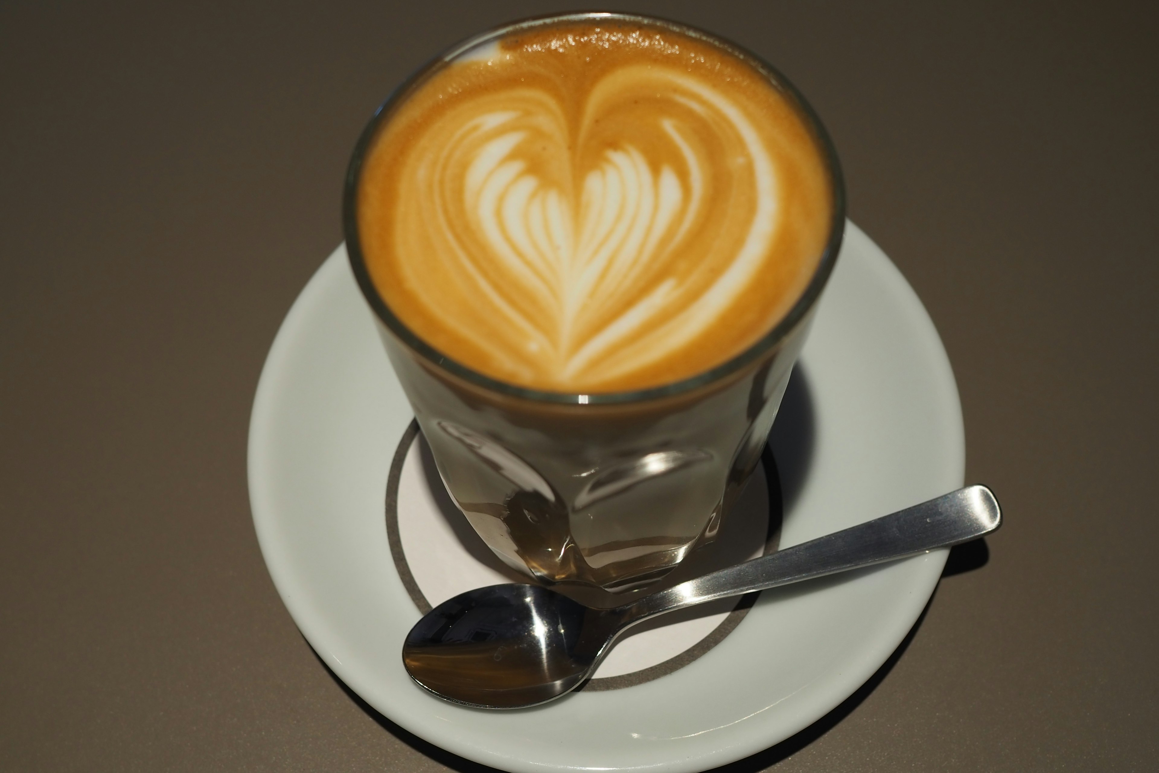 Caffè latte con arte del latte a forma di cuore in un bicchiere trasparente