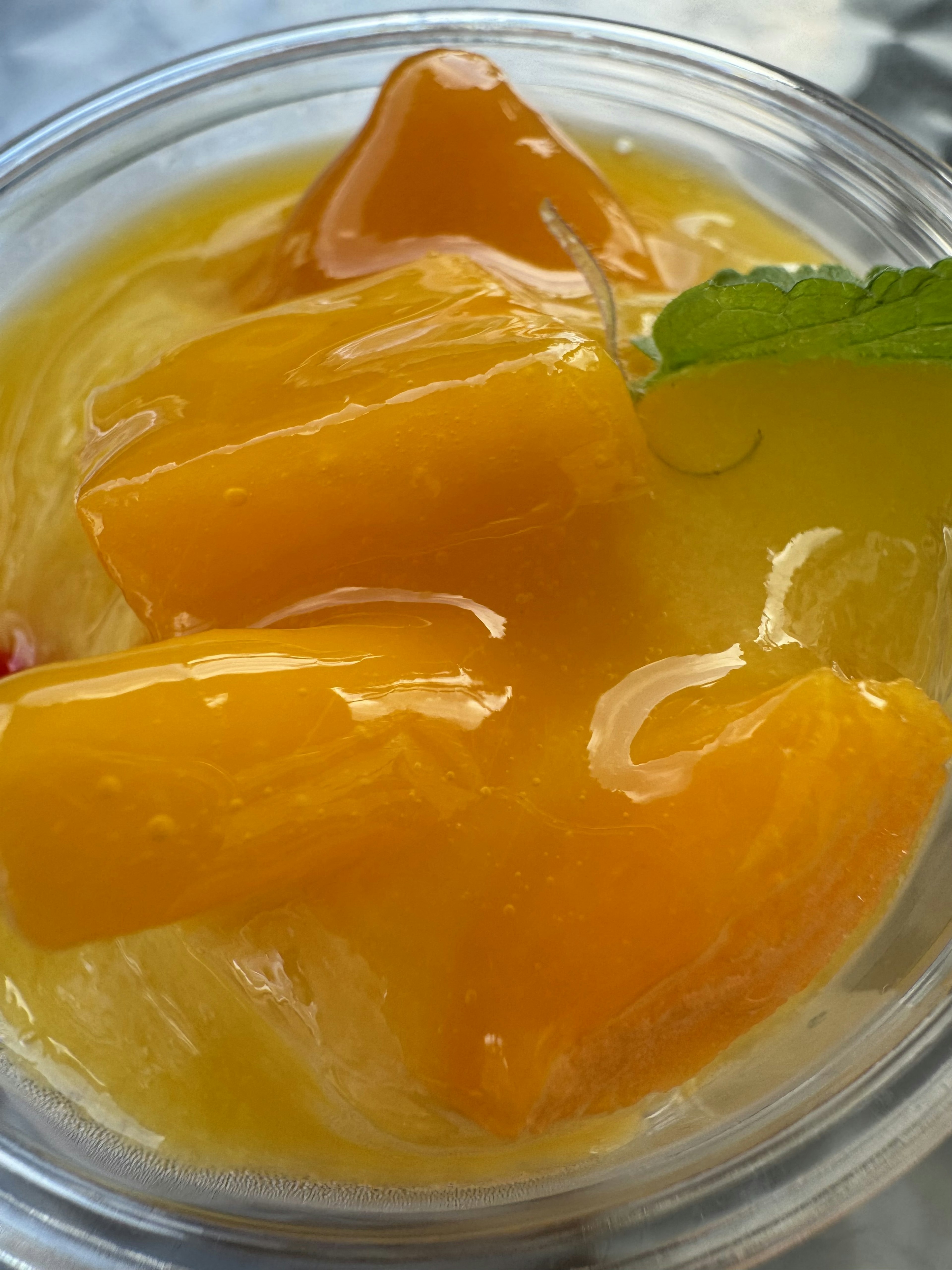 Close-up of vibrant mango dessert topped with fresh mint leaves