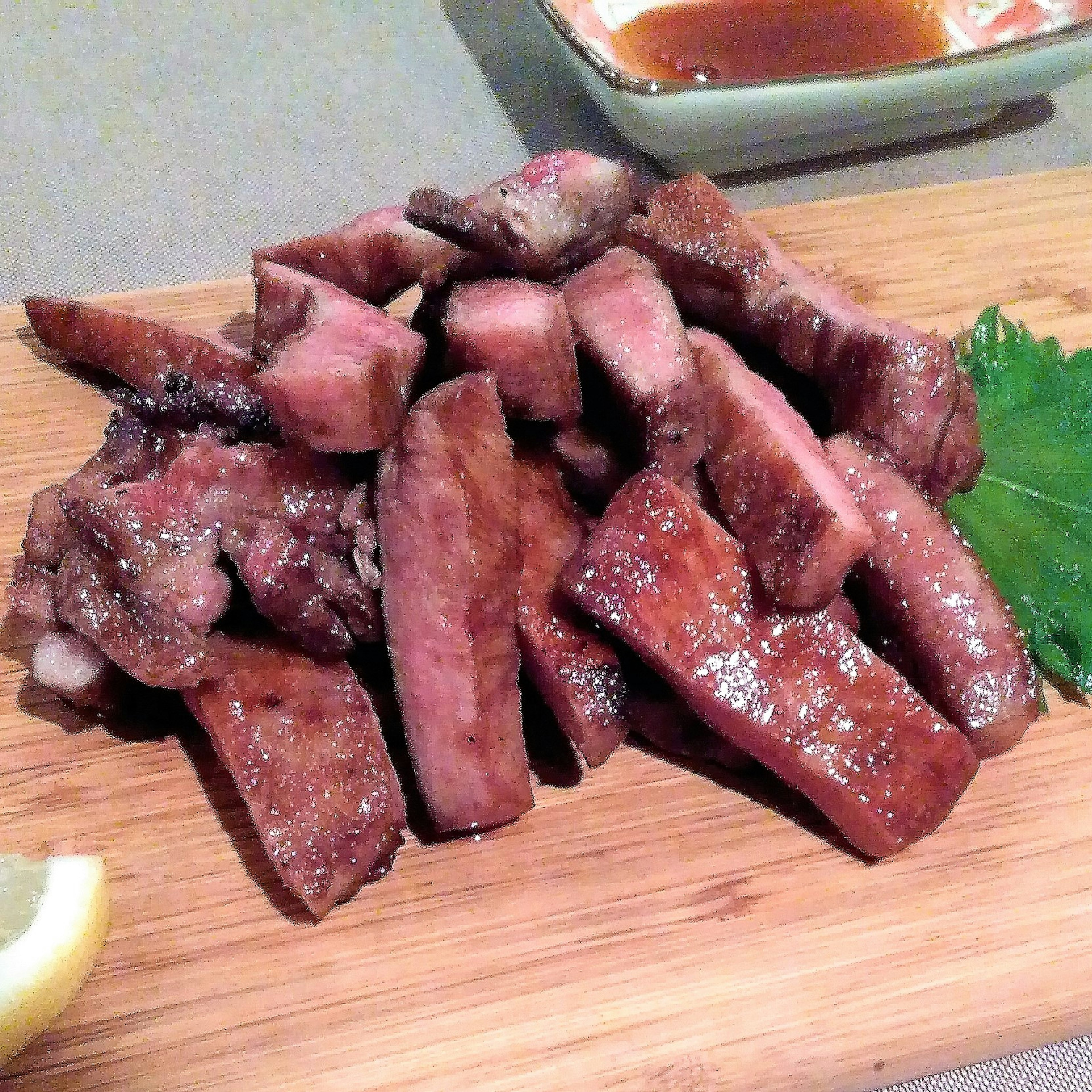 Un mucchio di carne grigliata disposto su un tagliere di legno