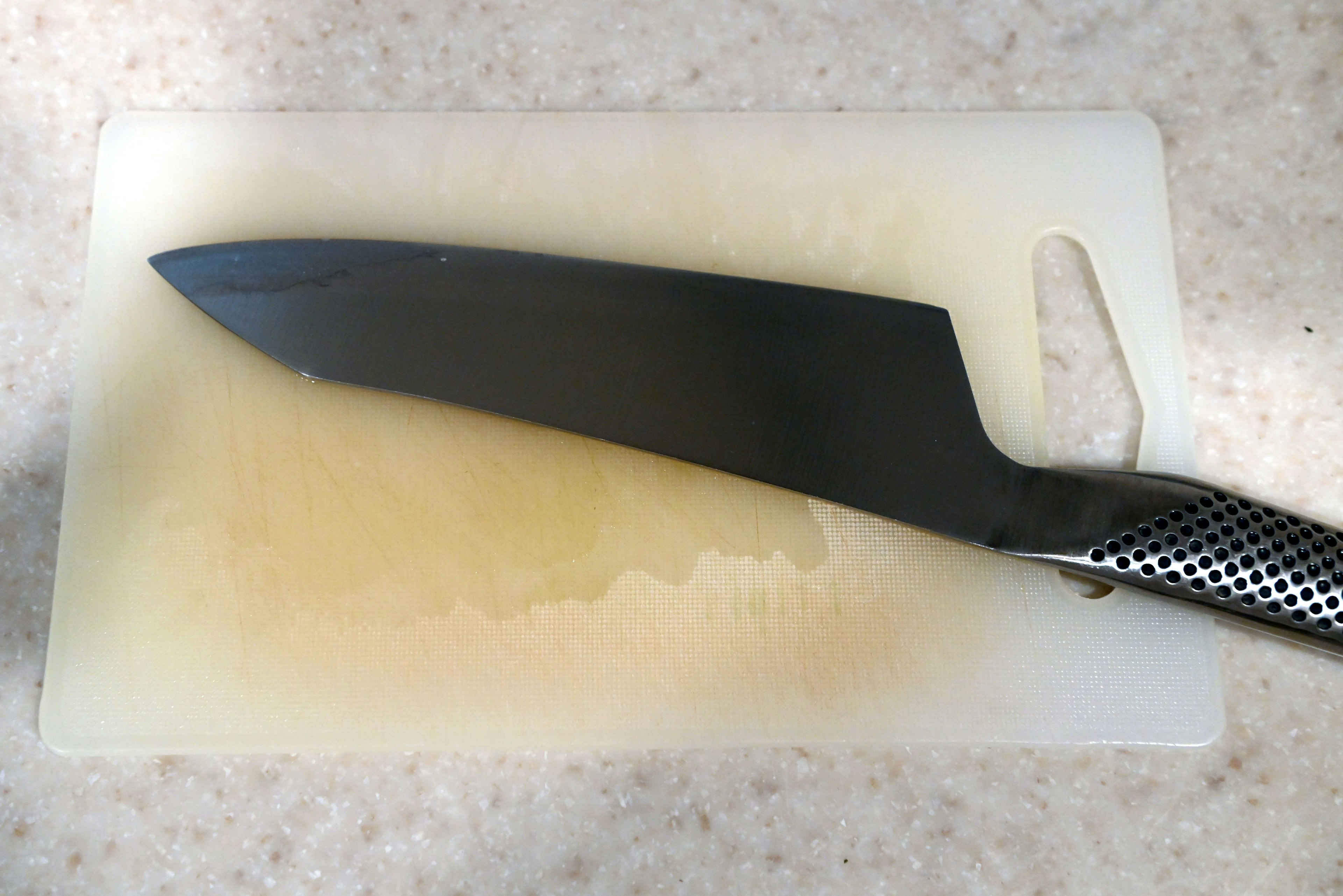 A black knife placed on a white cutting board