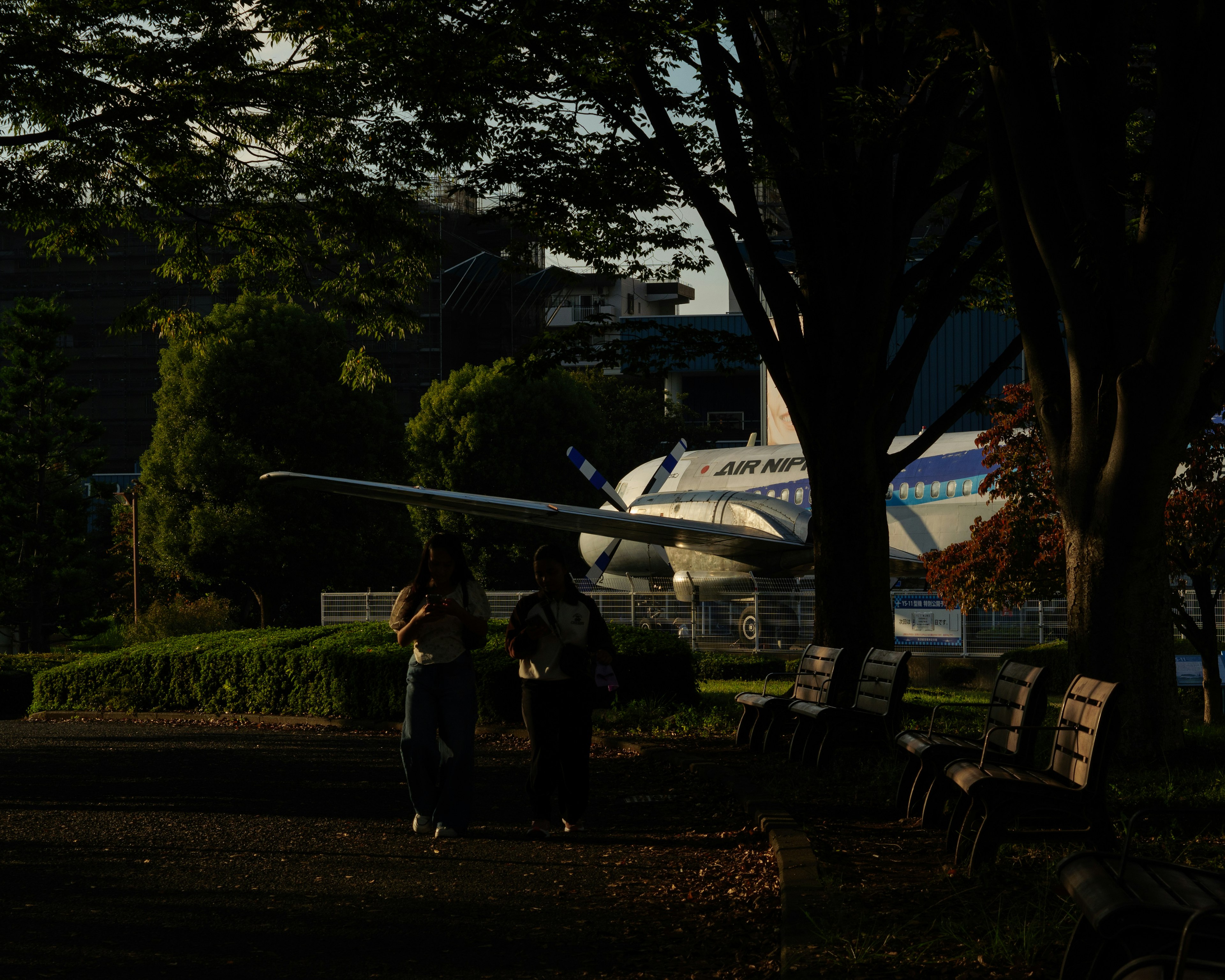 Zwei Personen gehen in einem Park mit einem Flugzeug im Hintergrund