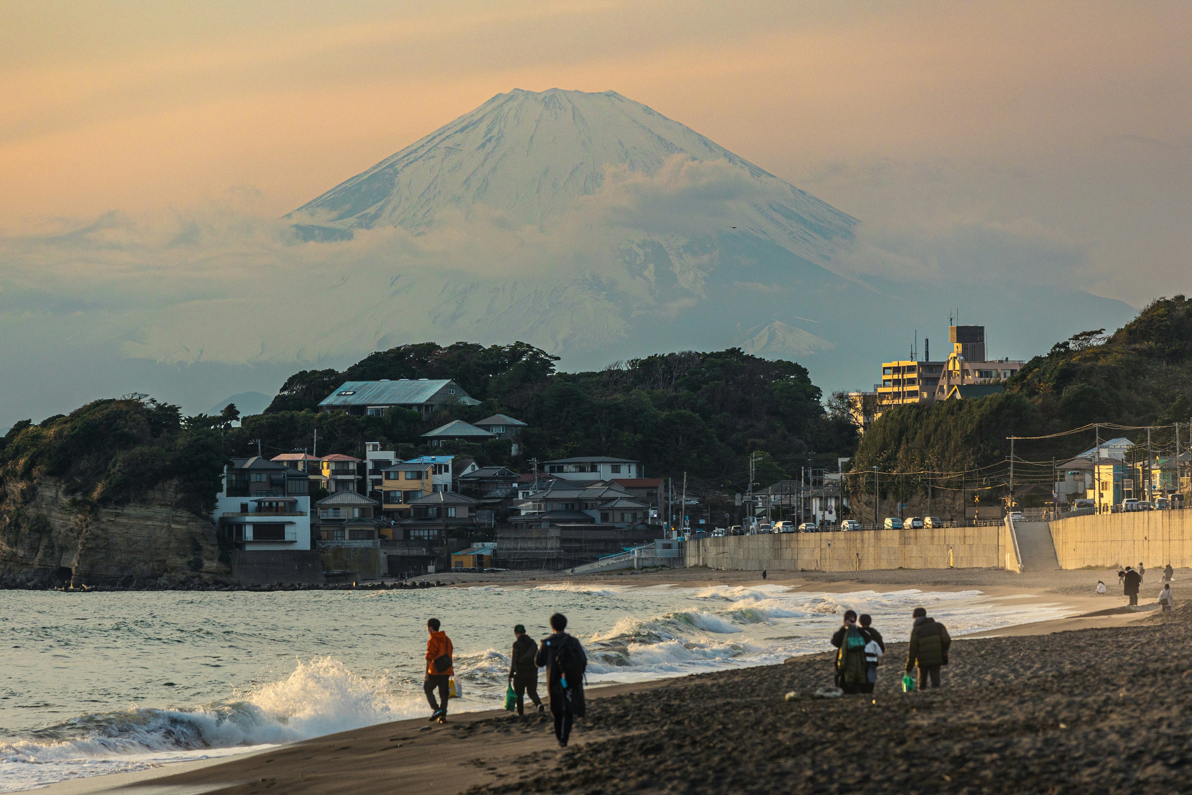 海岸で富士山を背景に散歩する人々の風景