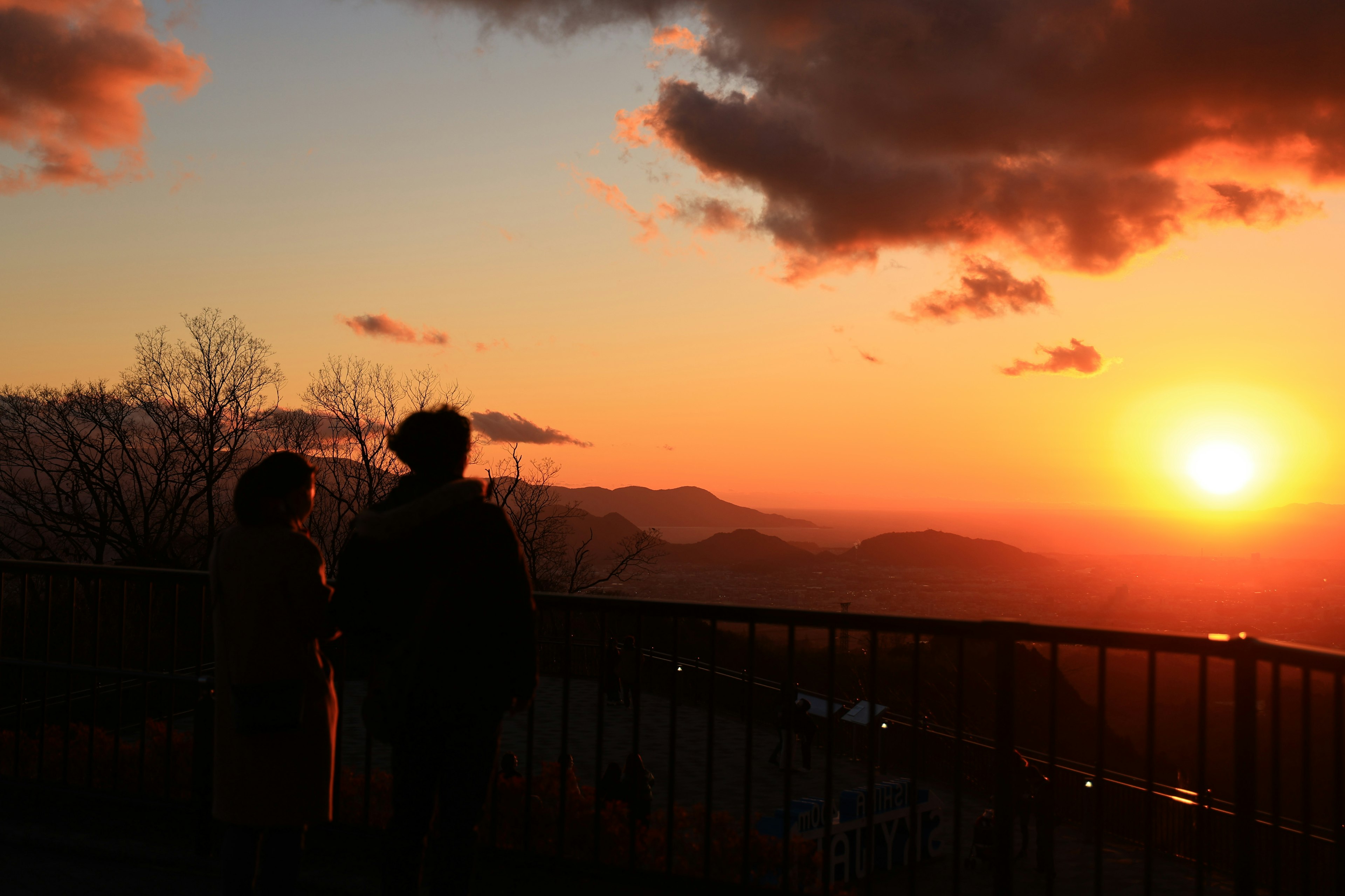 Schatten von zwei Personen, die einen Sonnenuntergang mit einem bunten Himmel betrachten