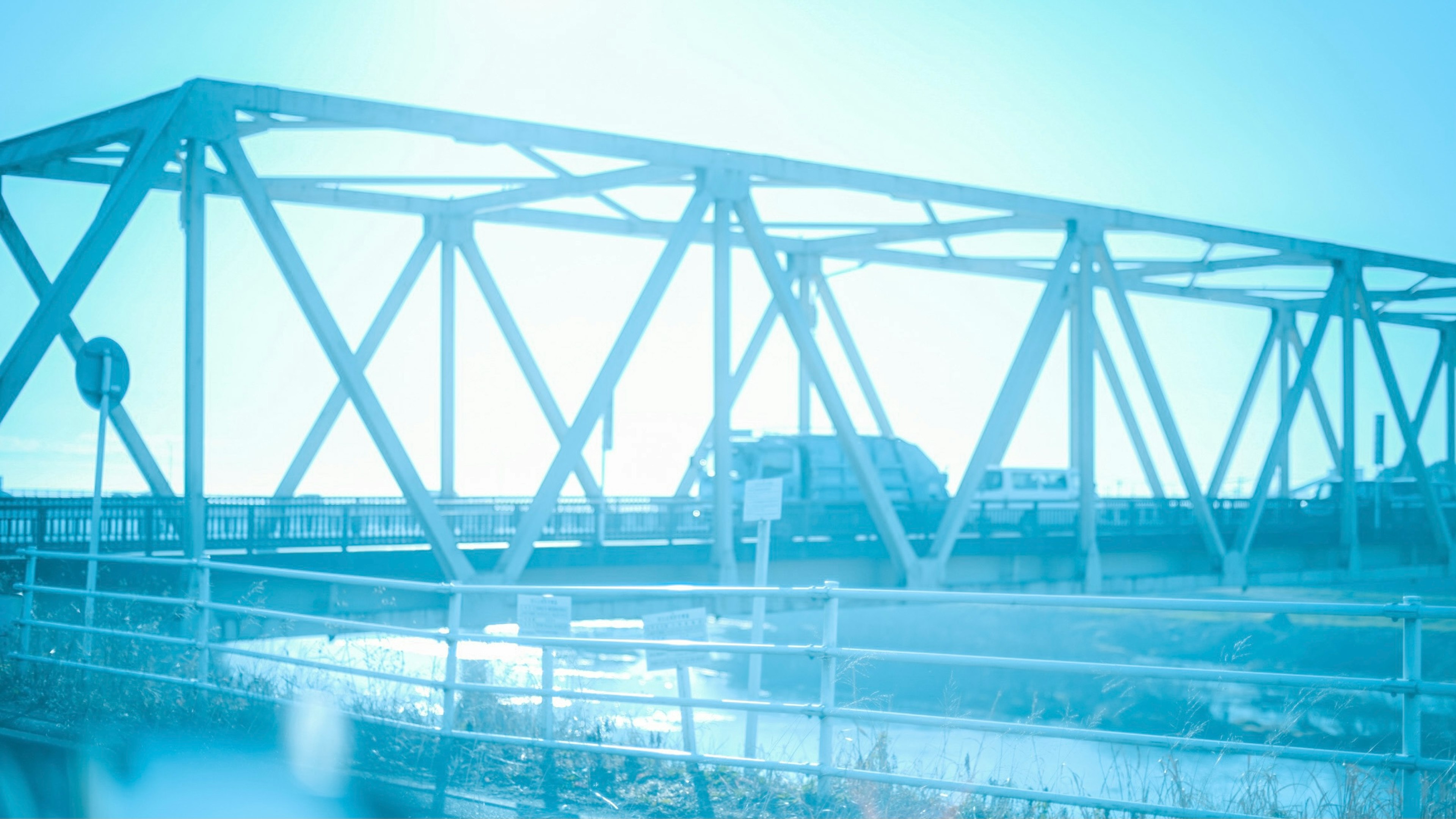 Una imagen azul de un puente de truss con vehículos cruzando