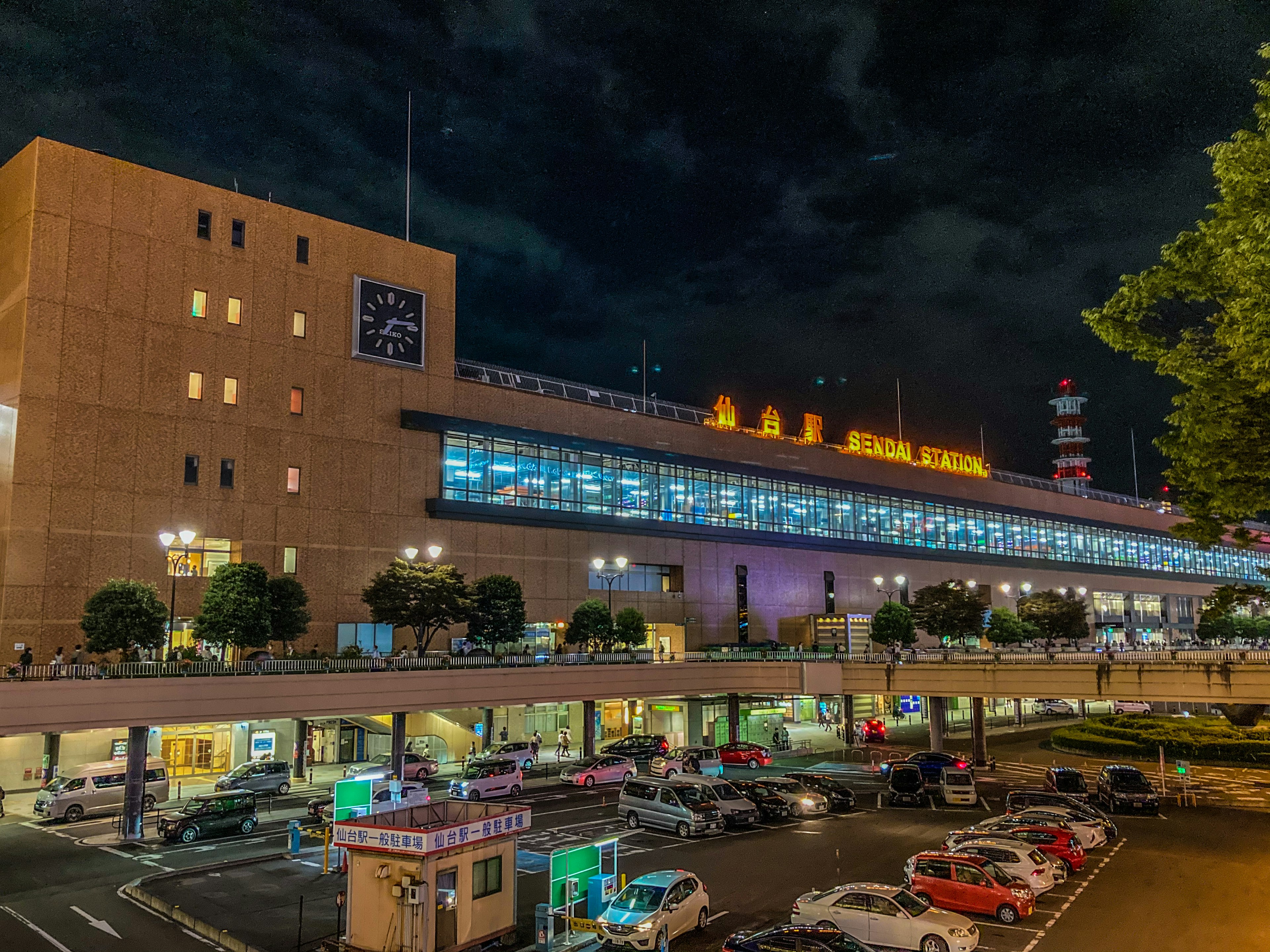 Vista nocturna de una estación de tren con aparcamiento