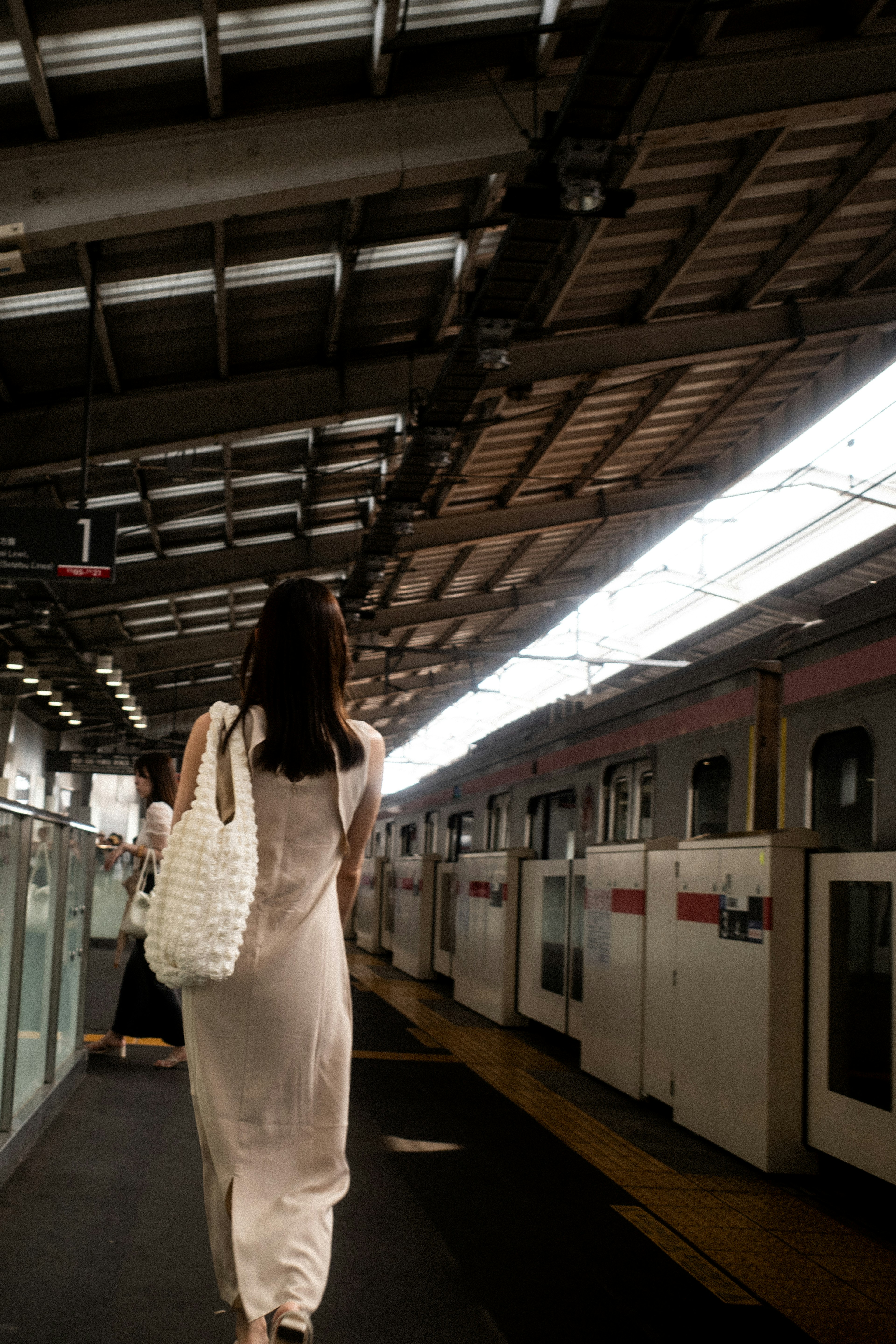 Una mujer caminando hacia un tren en una estación