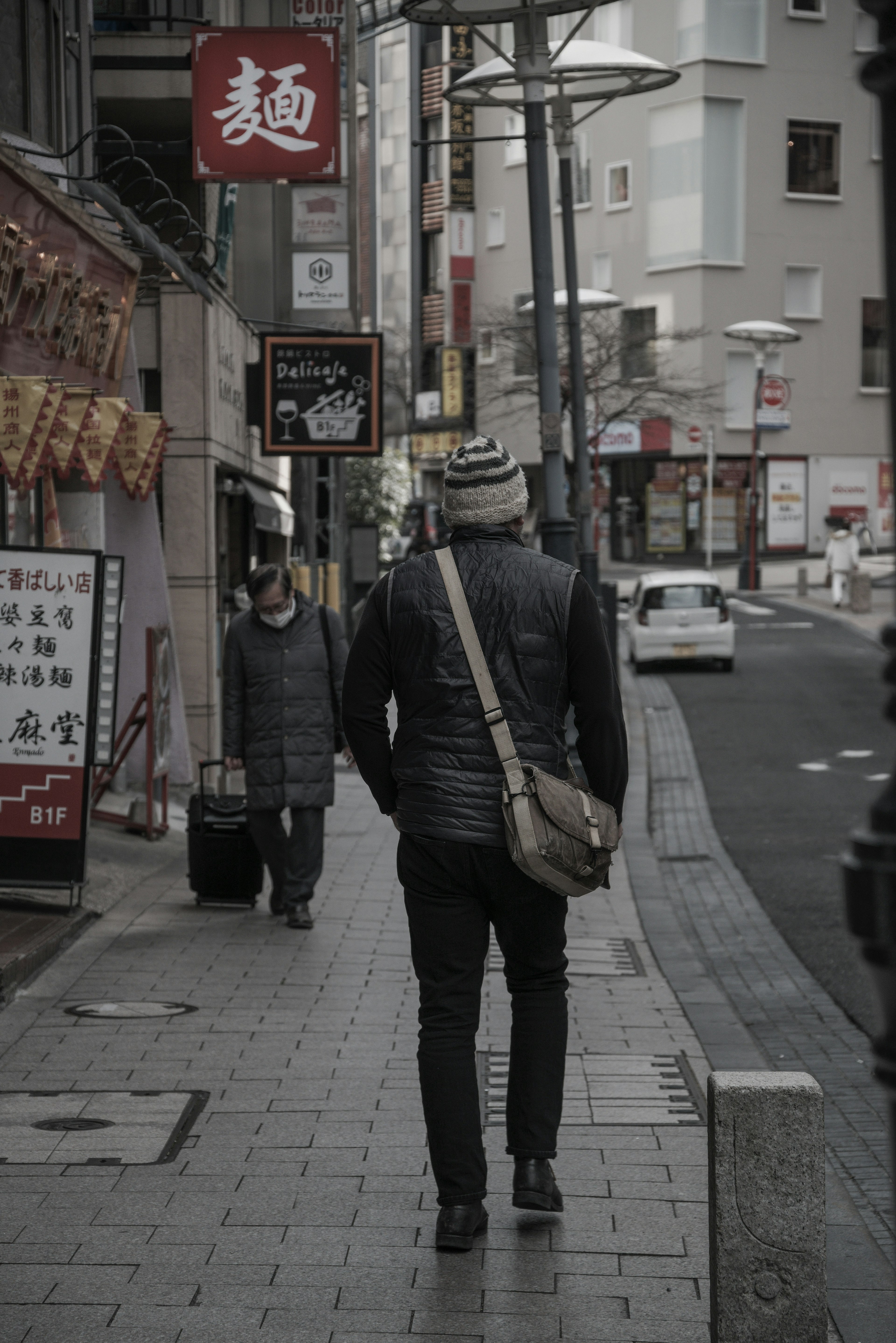 街を歩く男性と女性の後ろ姿ビルや看板が見える