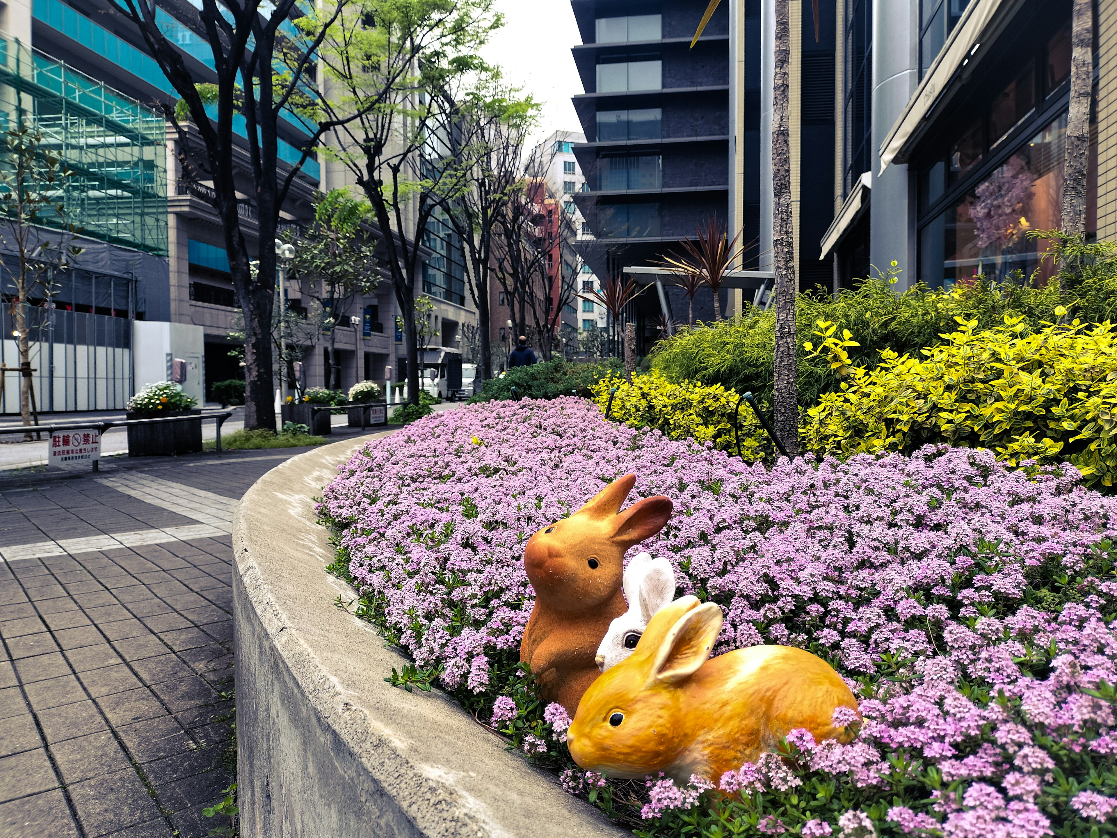 Colorful flower bed with cute rabbit sculptures in an urban setting