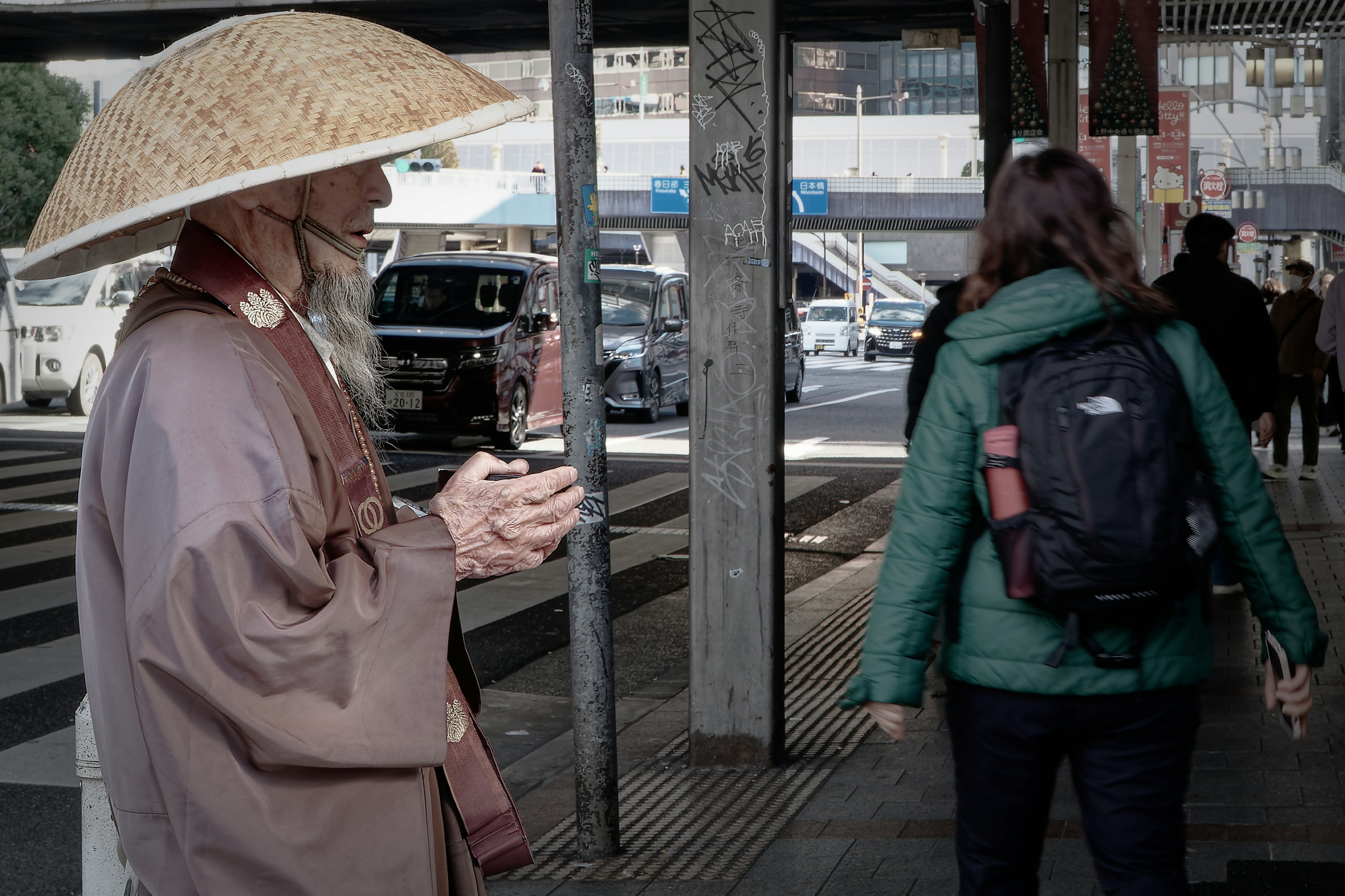 一位穿著傳統服裝的老人戴著草帽站在人行道上