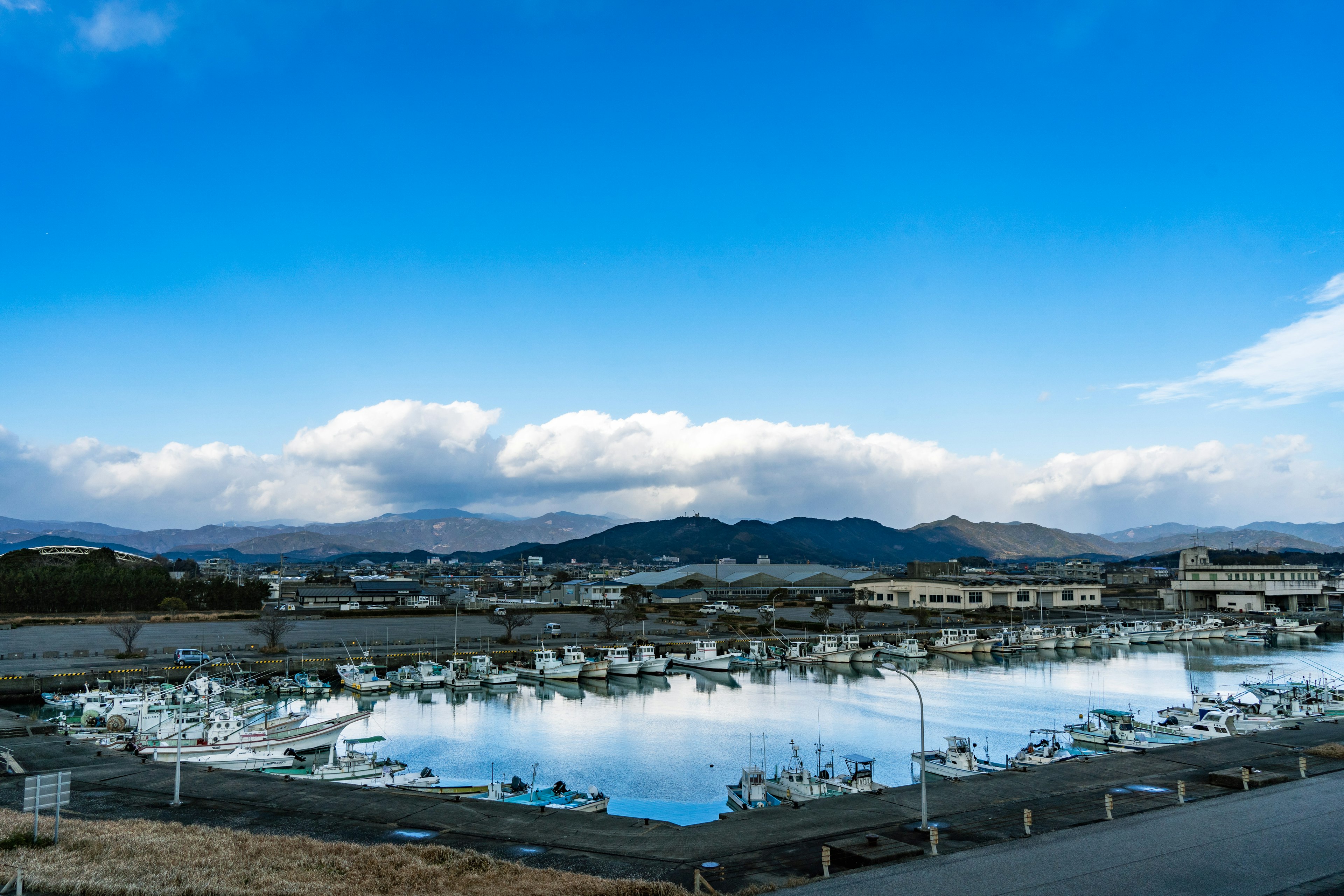 Paysage marin serein avec ciel bleu clair bateaux alignés dans le port et montagnes environnantes