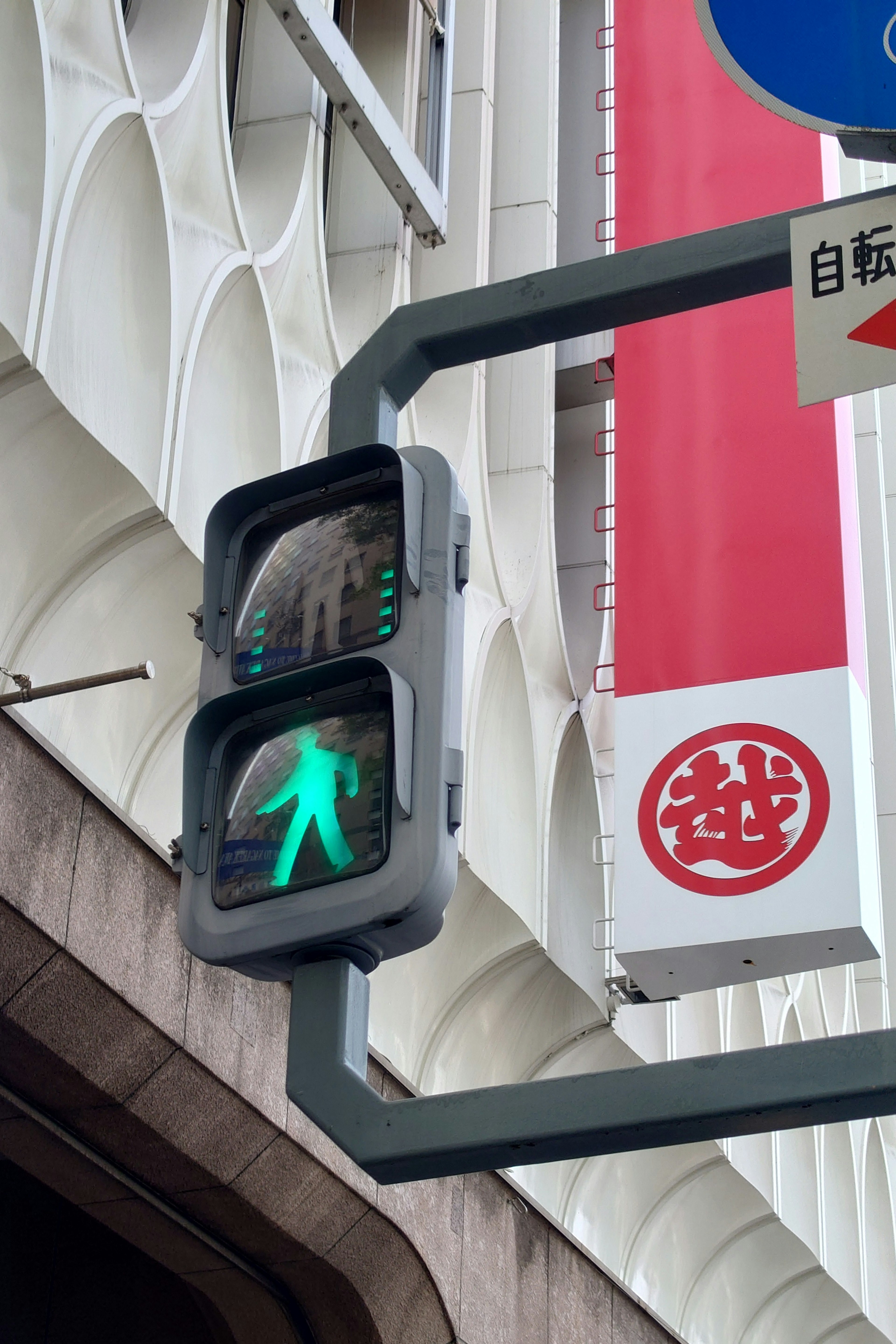 Green pedestrian signal illuminated with traffic sign and building background